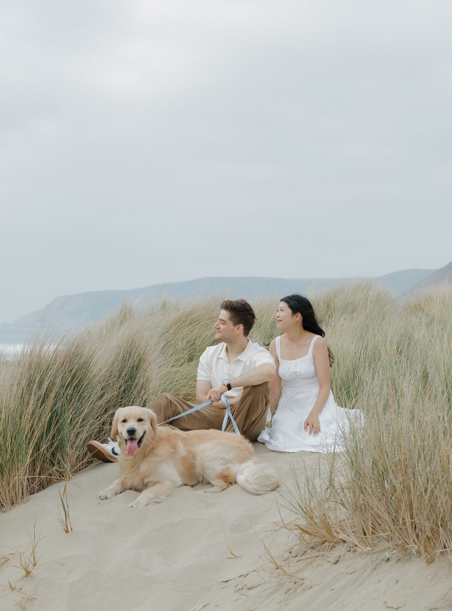 Couple sitting on the beach with their dog for engagement photos