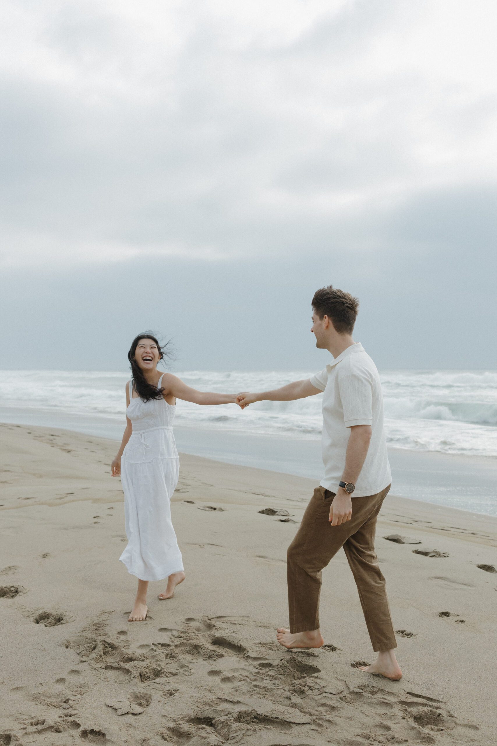 A couple walking down the beach holding hands during engagement photos