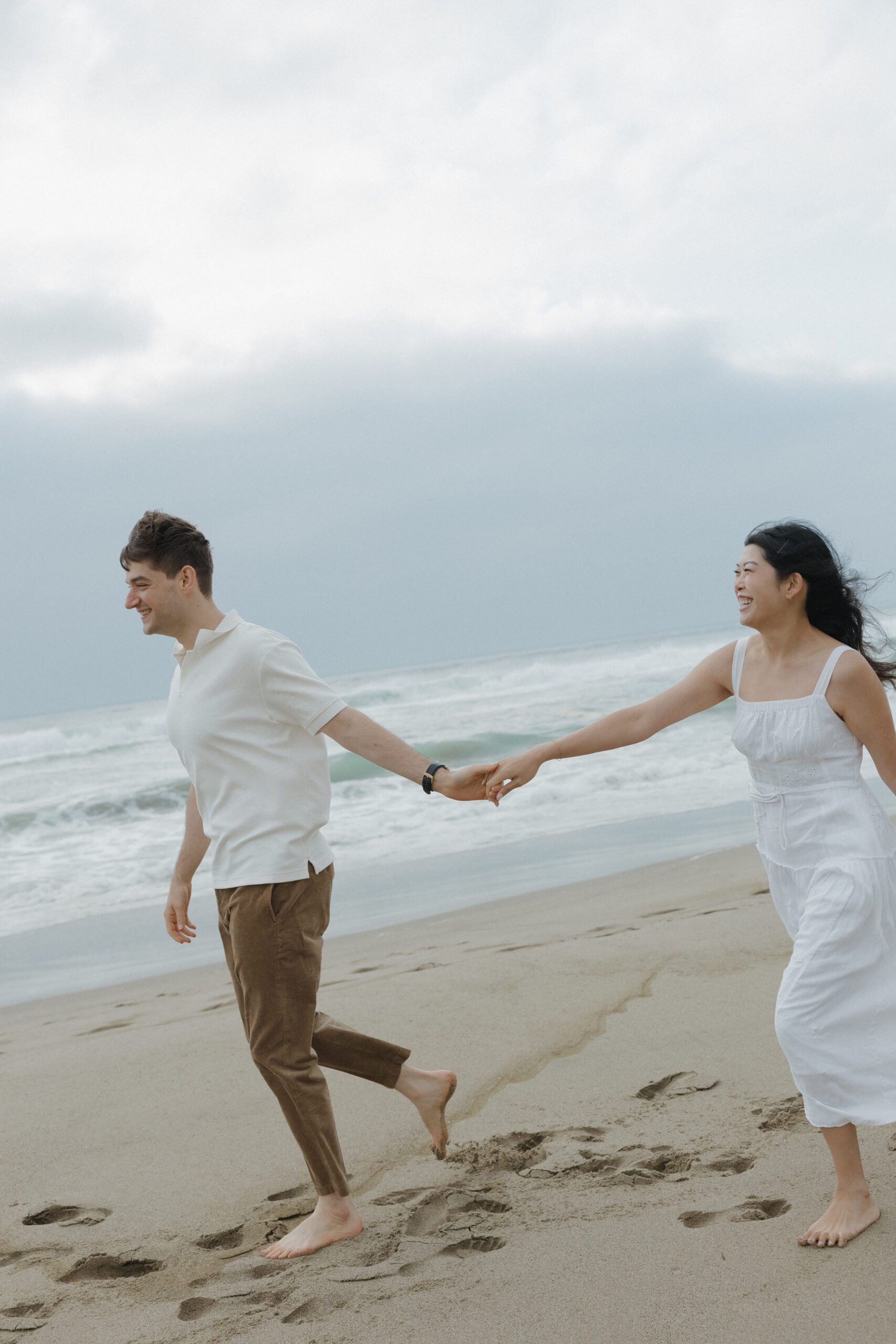 A couple walking on the beach fore engagement photos