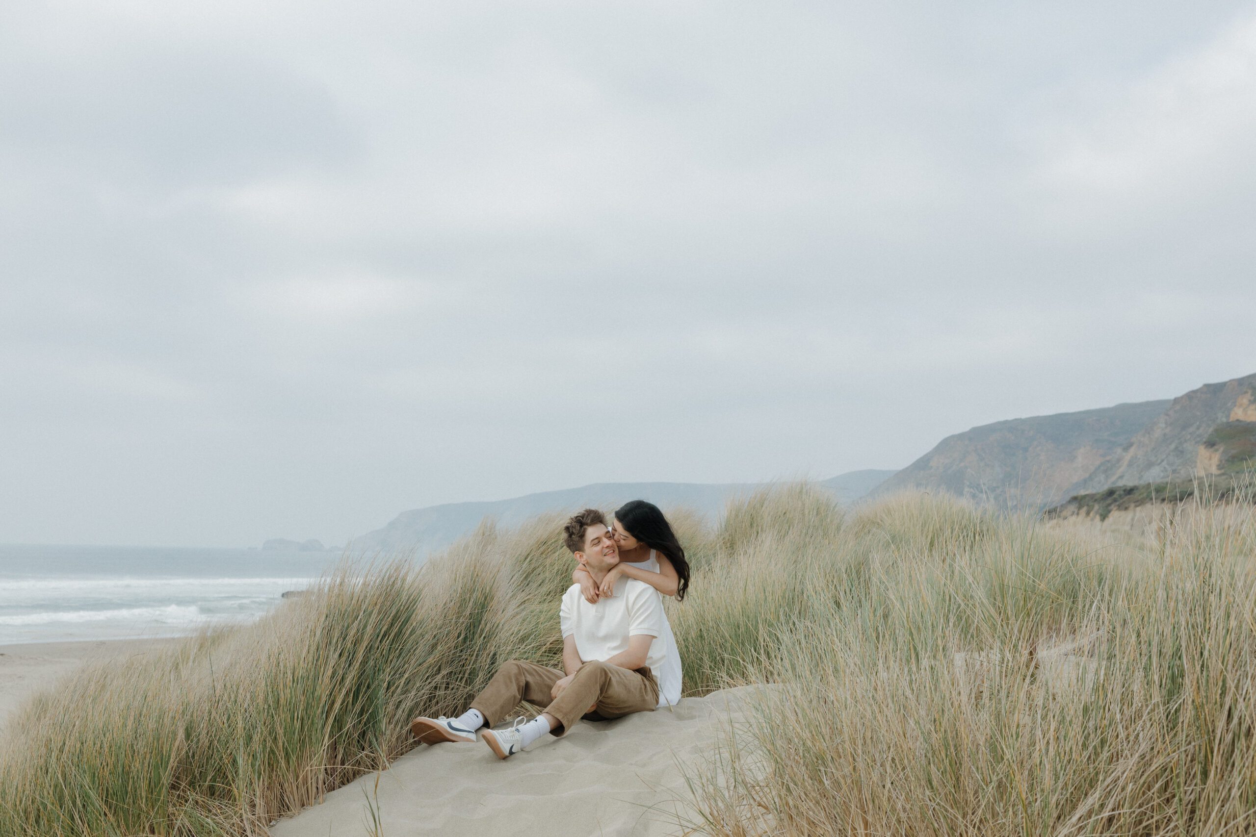 A girl hugging and kissing her fiancee from behind