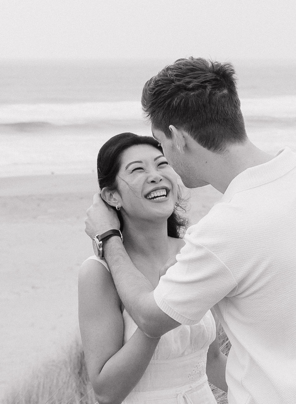 Film-inspired engagement photo of man tucking hair behind his fiancees ear