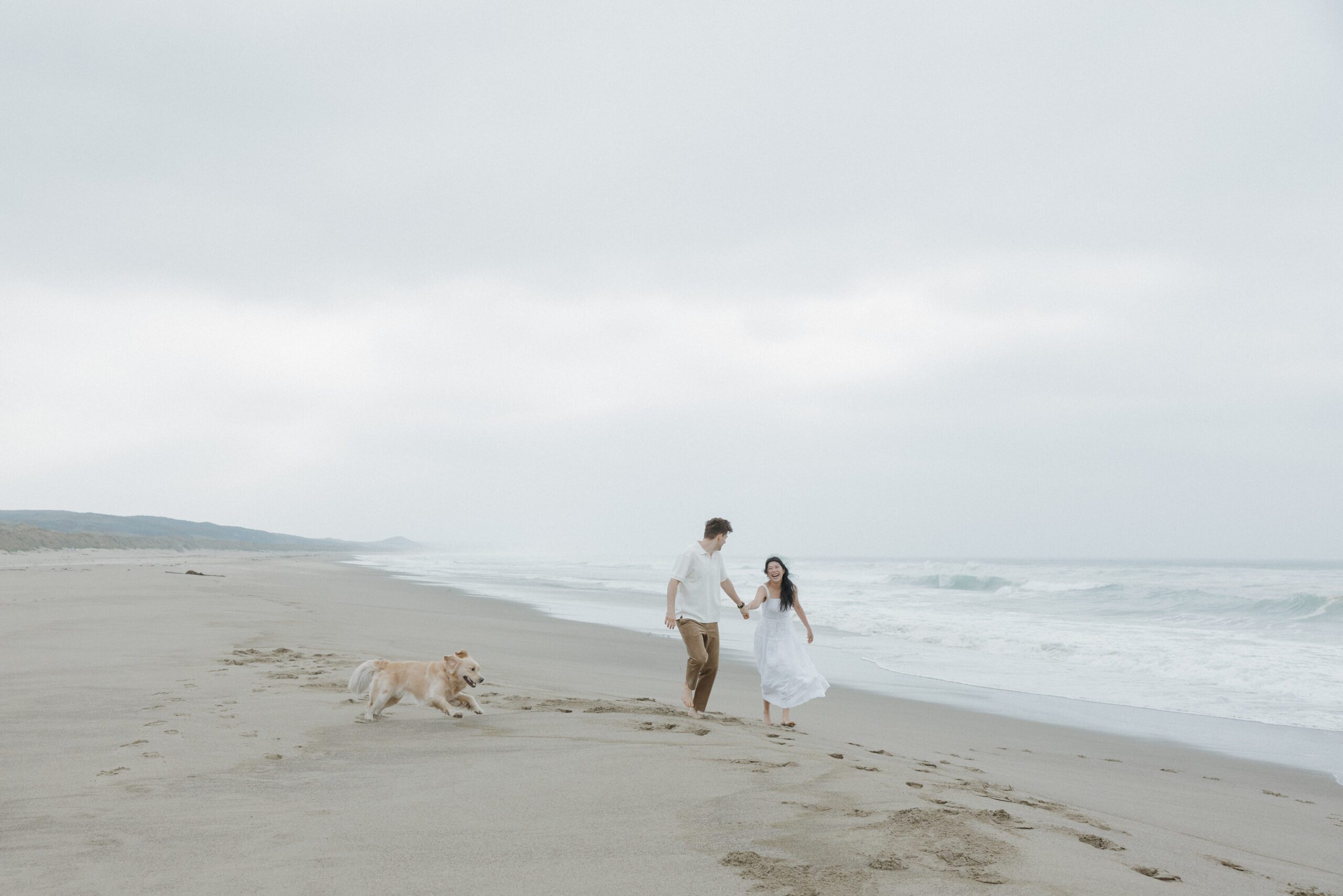 Couple laughing while walking on the beach during beach engagement photos