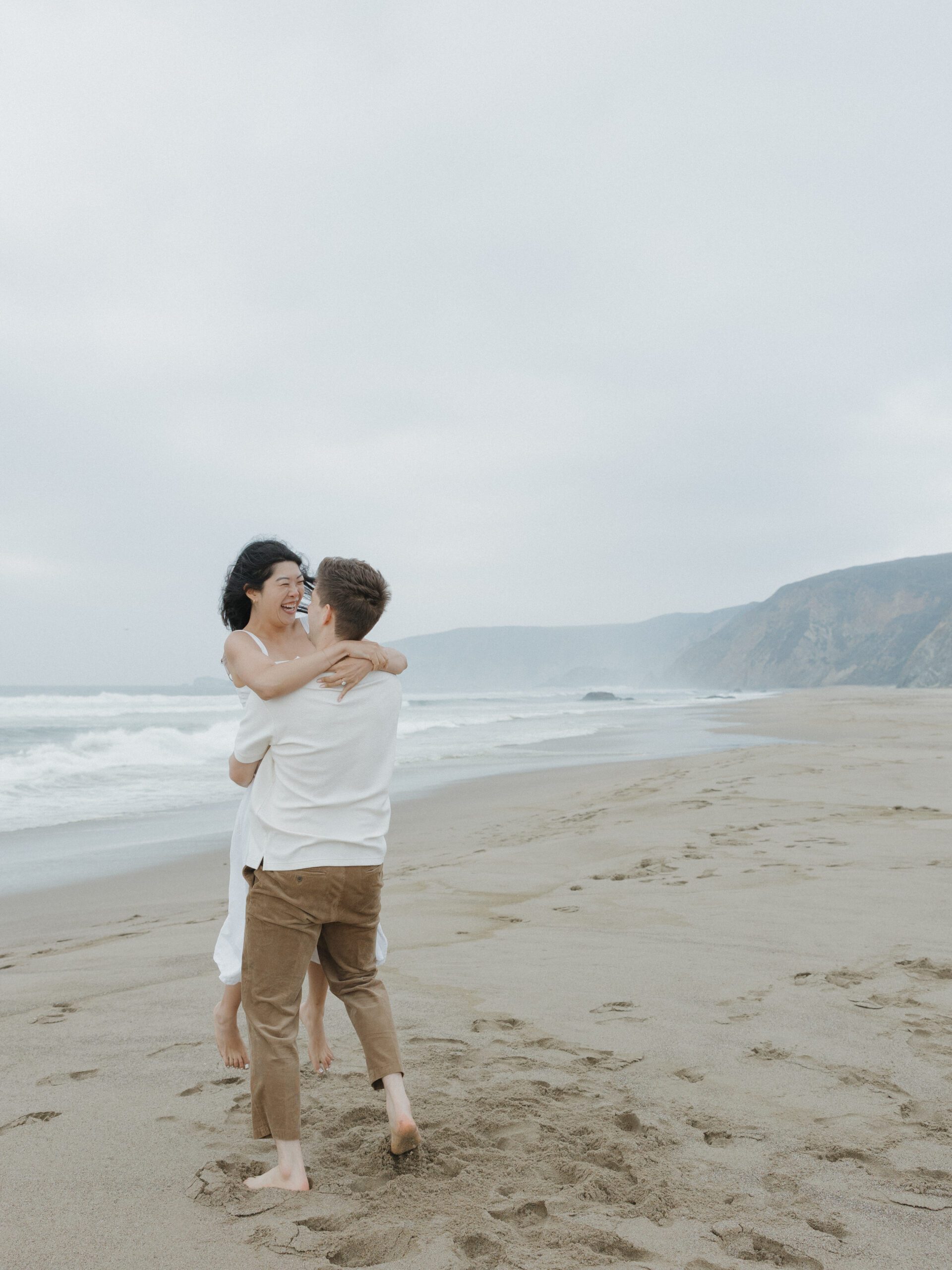 A couple spinning at their beach engagement photoshoot