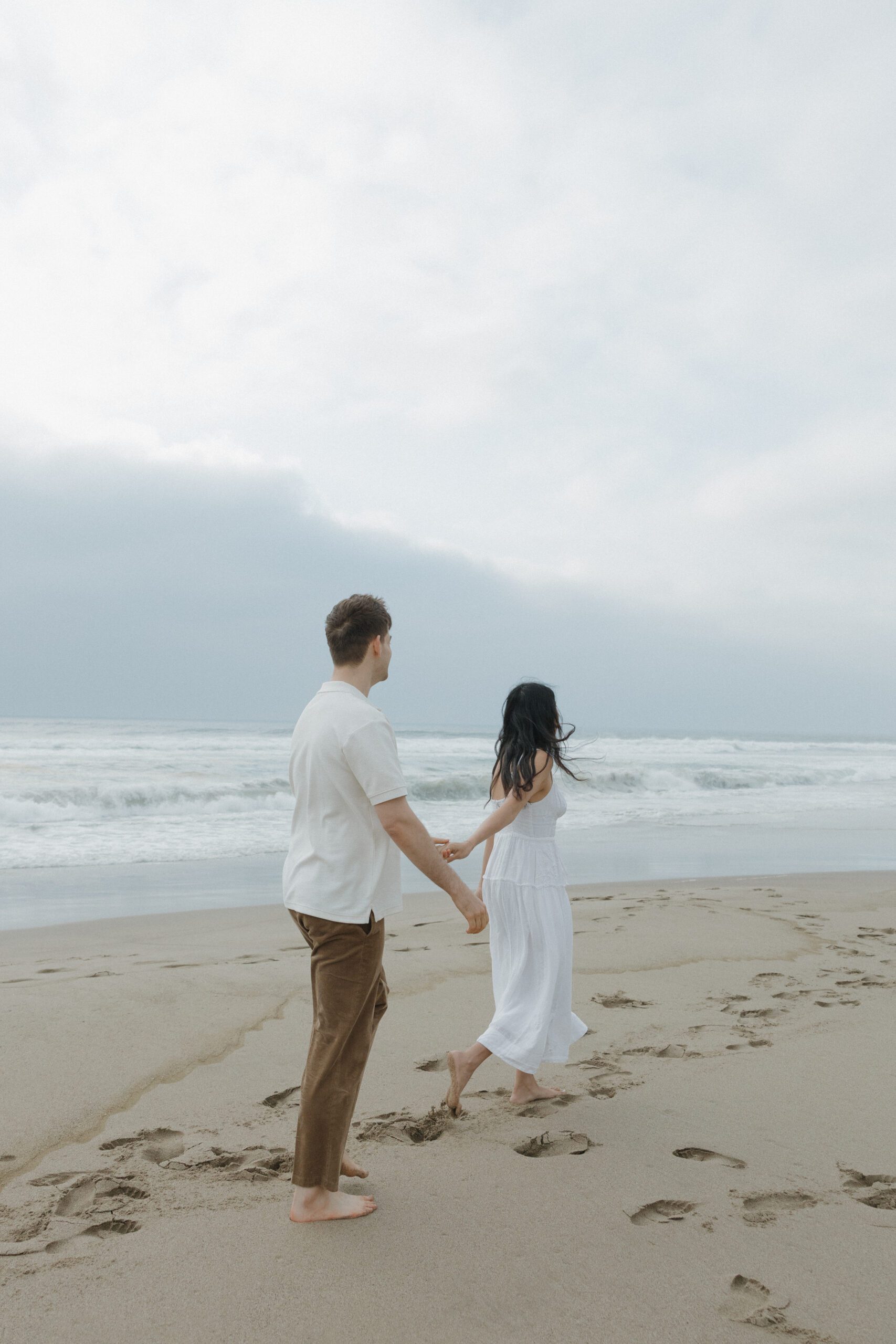 A couple walking on the beach in editorial engagement photos