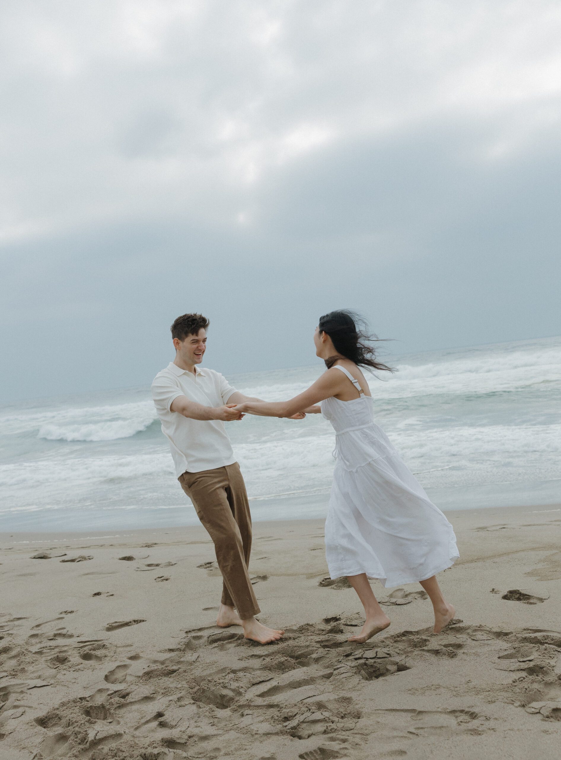 Couple spinning on the beach during engagement photoshoot