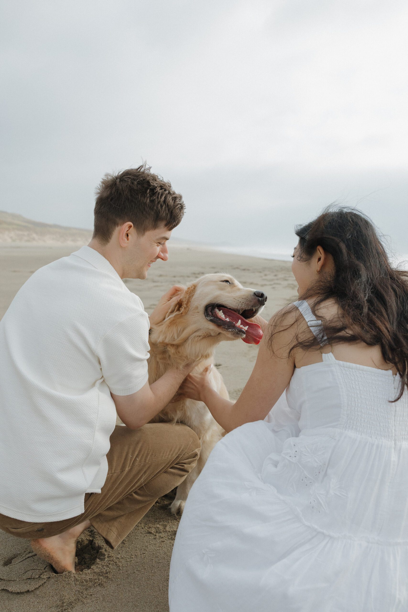 Couple playing with their dog on the beach during their engagement photoshoot