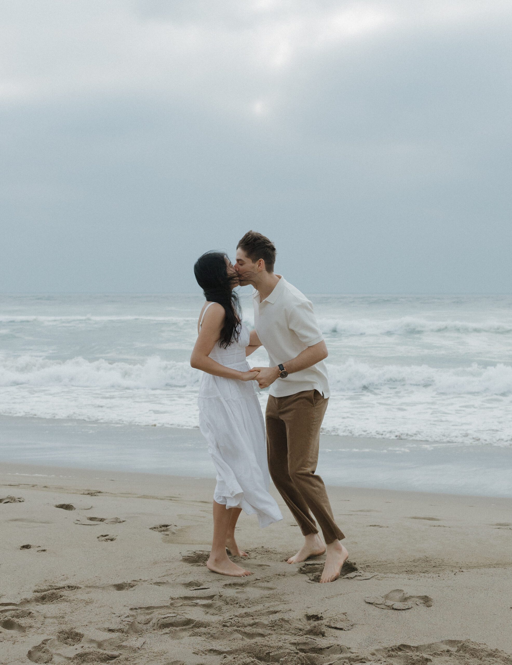 Couple kissing on the beach as an engagement photo pose