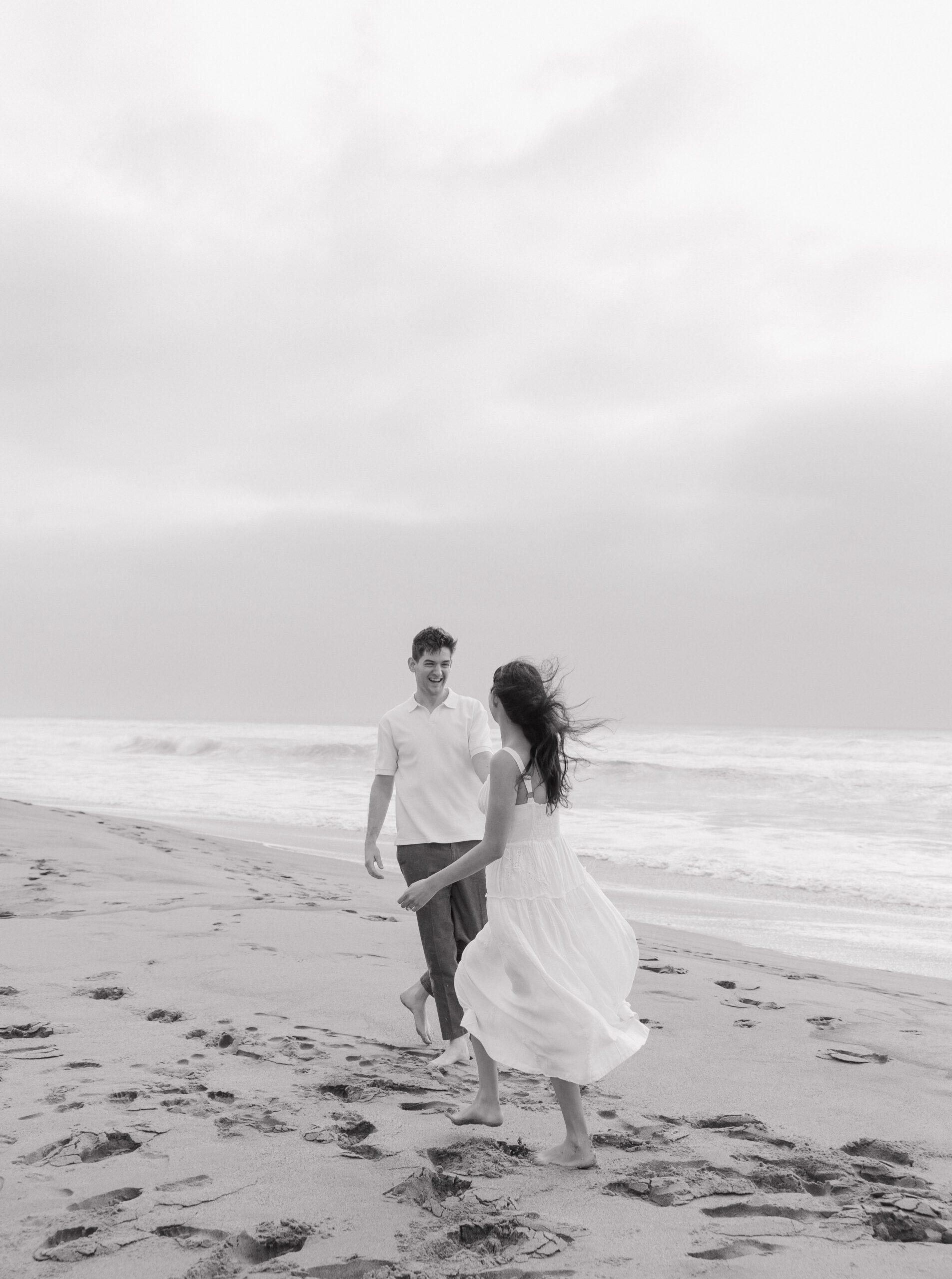 Couple running on the beach during their engagement photoshoot