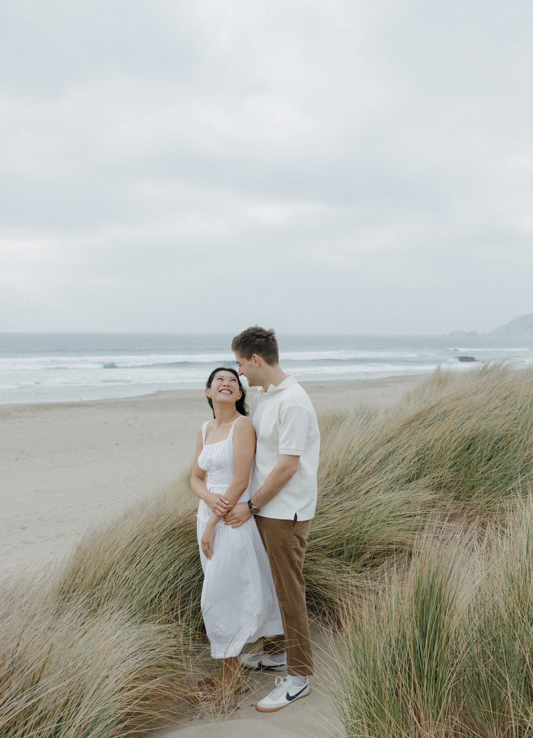 A couple smiling at each other on the beach during engagement photos