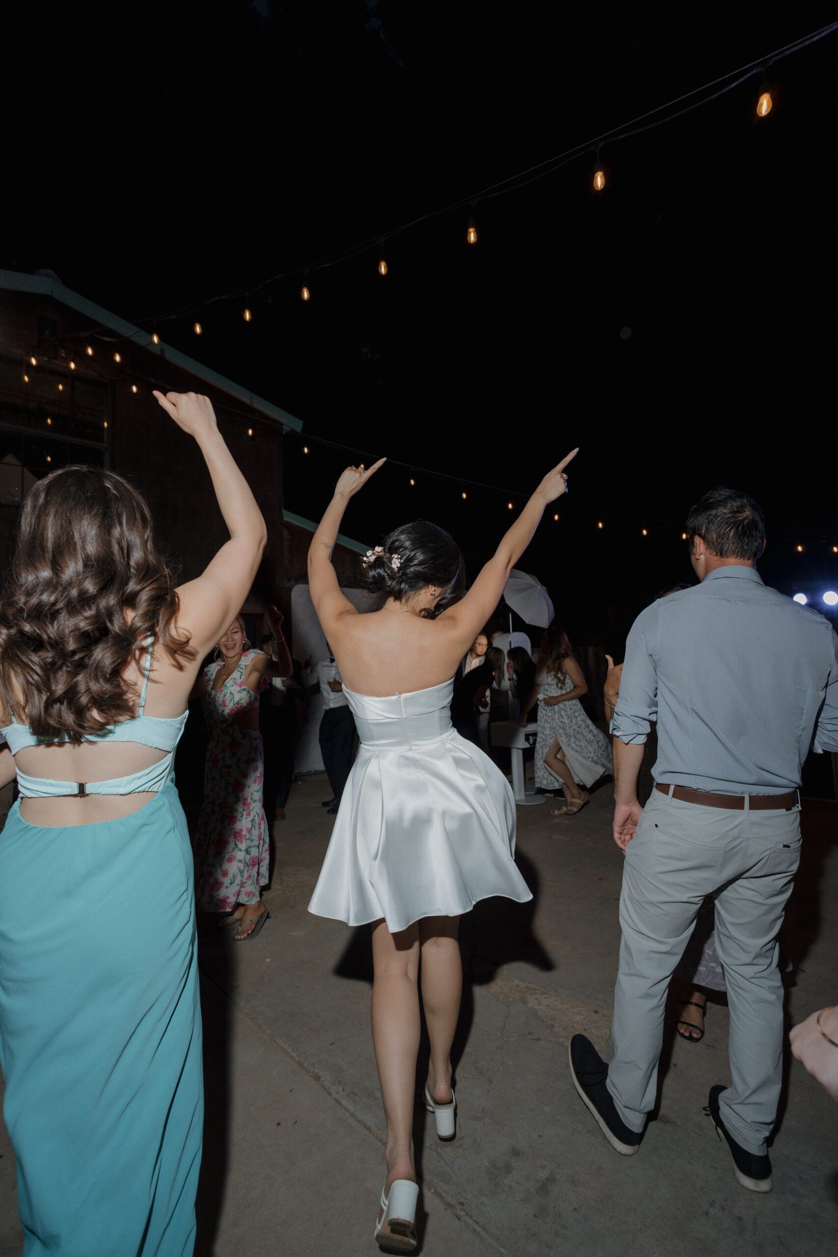 A bride dancing in her short wedding reception dress at an intimate wedding reception