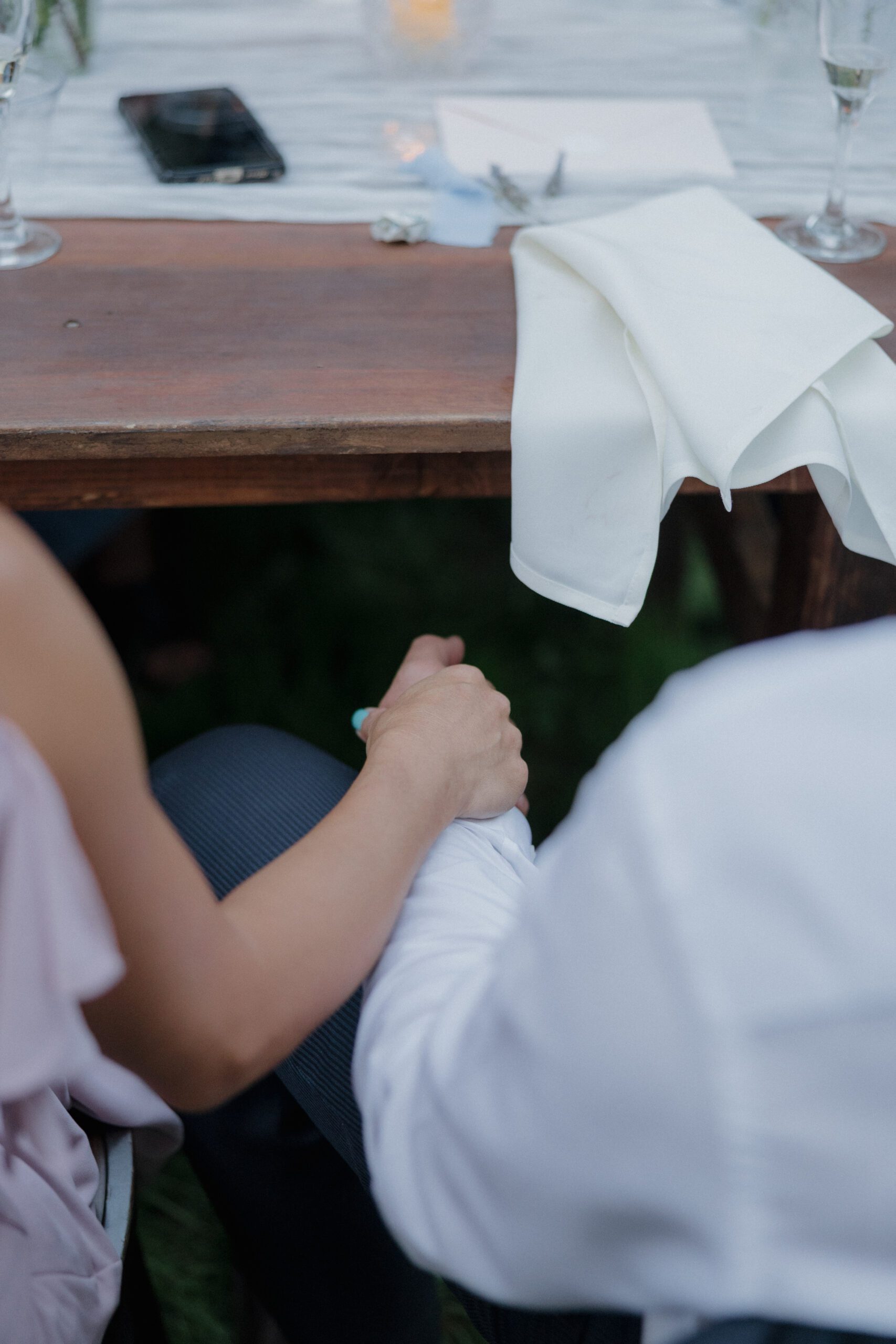 A documentary style wedding photo of a couple holding hands 