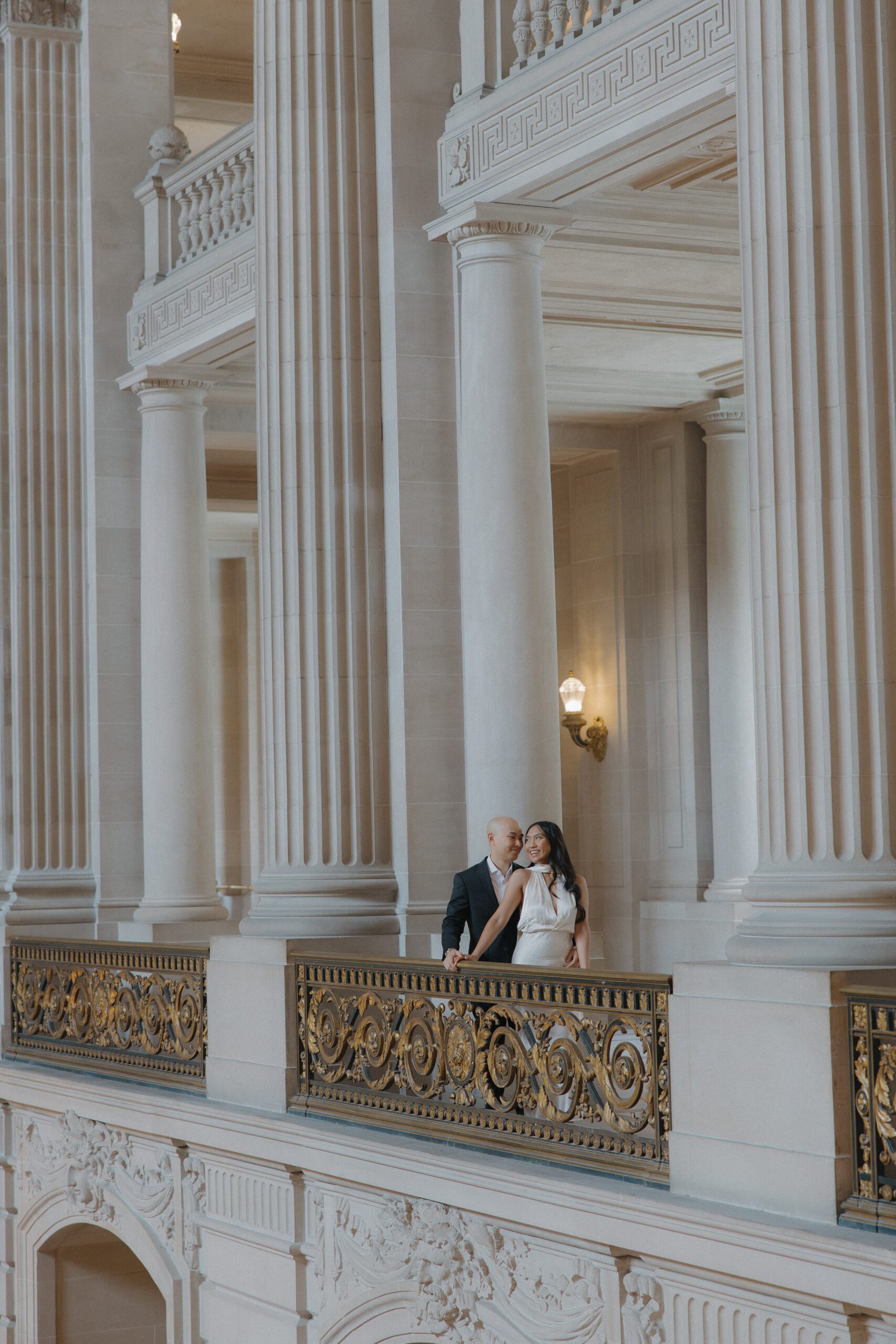 A couple posing for their engagement photoshoot at the MAyor's Balcony at San Francisco city hall