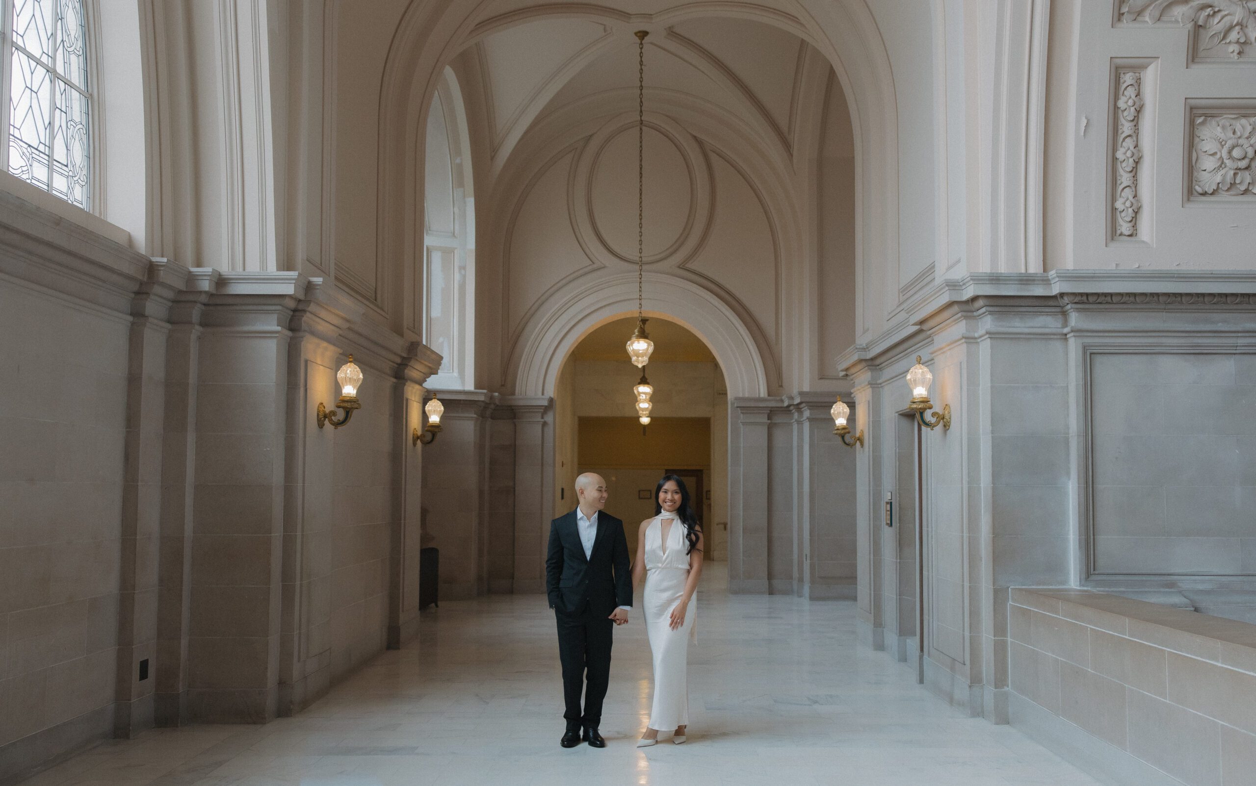 A couple posing for their engagement photoshoot in the hallway at San Francisco city hall