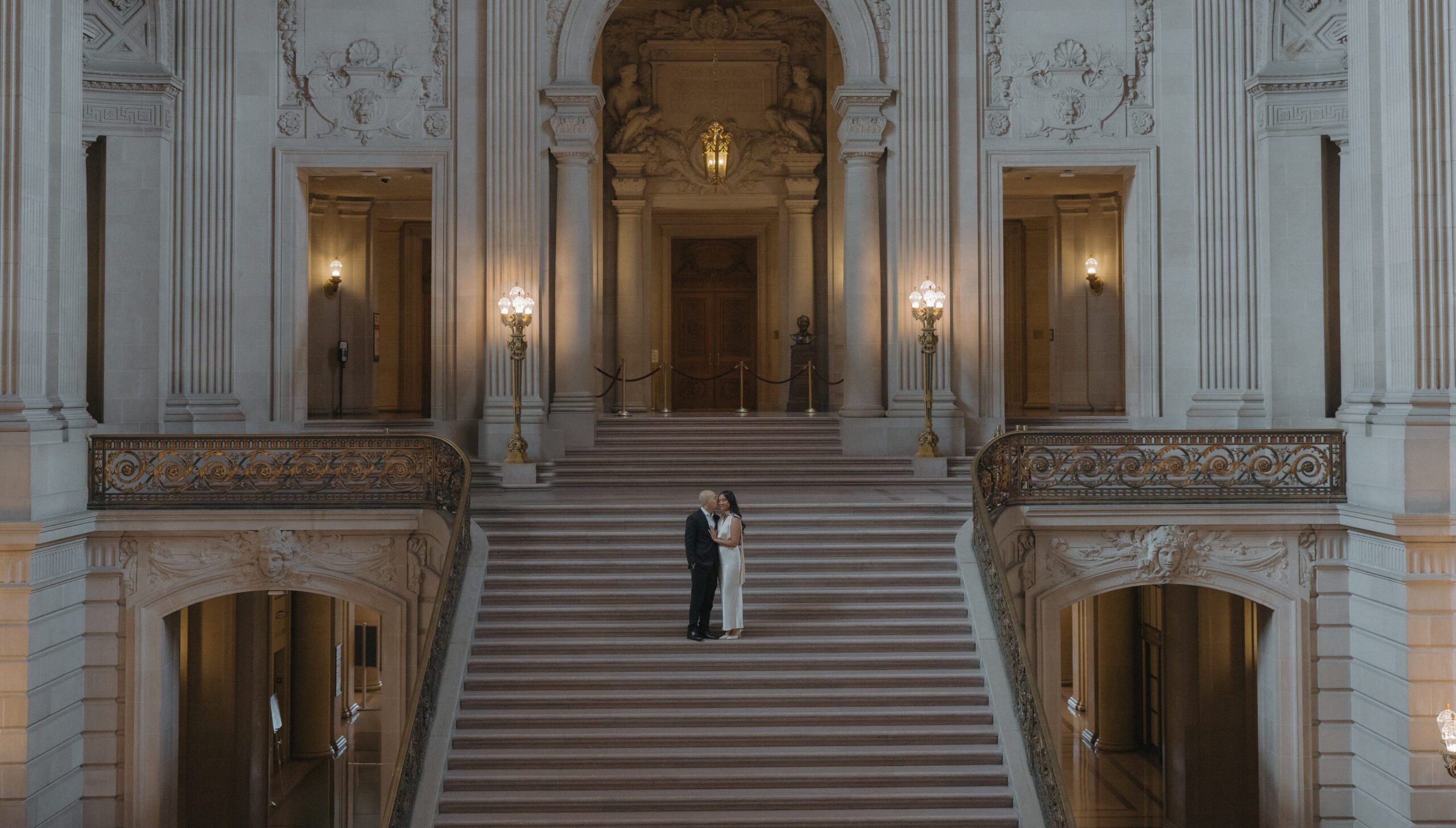A couple posing for San Francisco City Hall photos on the grand staircase