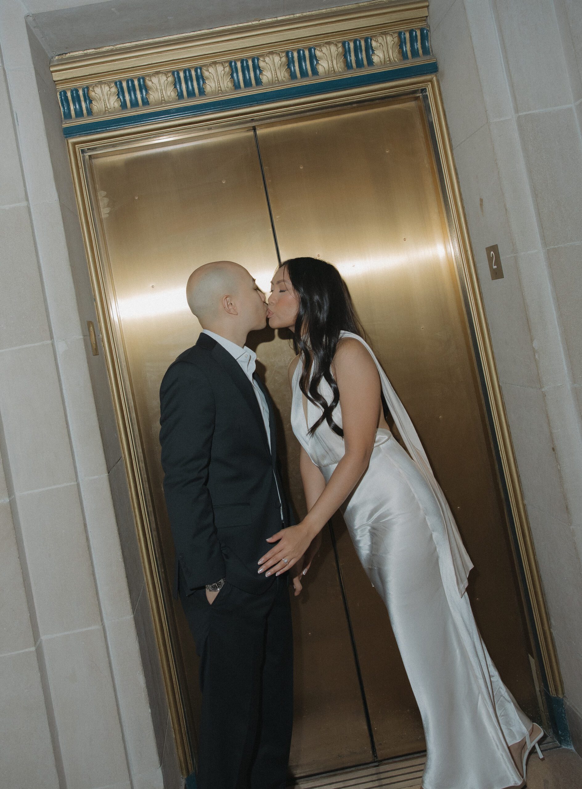 A couple kissing in front of elevator doors at San Francisco City Hall engagement photoshoot
