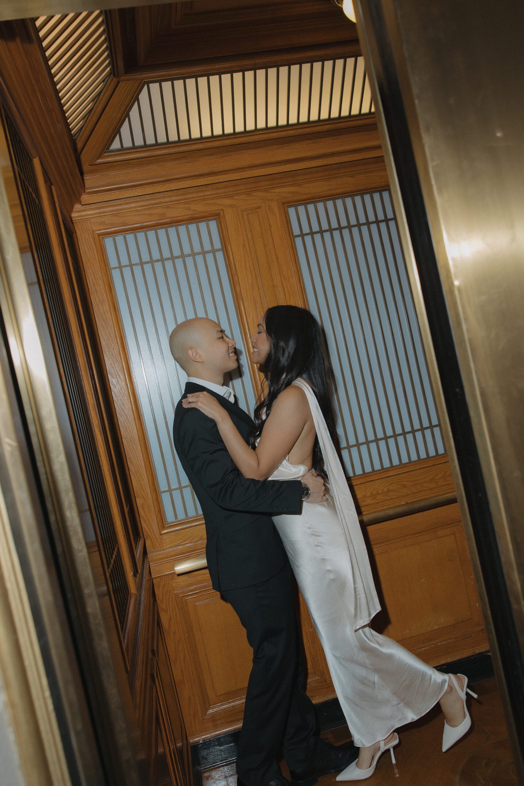 A couple leaning in for a kiss in an elevator at San Francisco City Hall