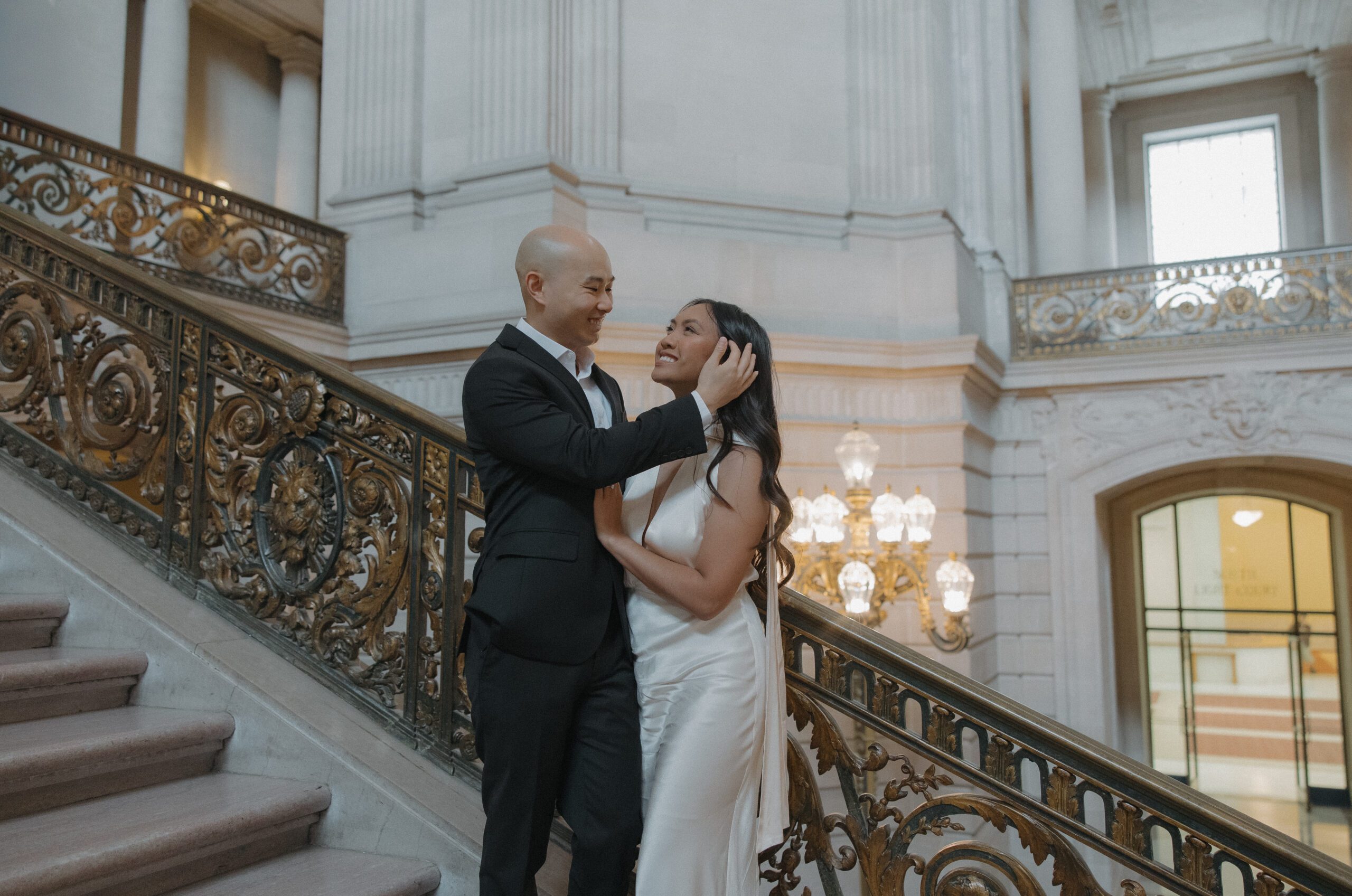 A man tucking his fiancees hair behind her ear during engagement photos