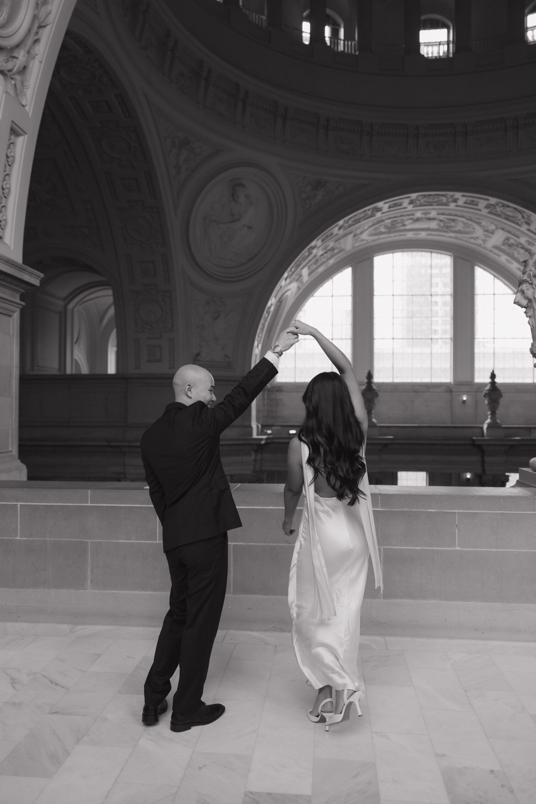 A black and white photo of a couple dancing during their engagement photoshoot at city hall