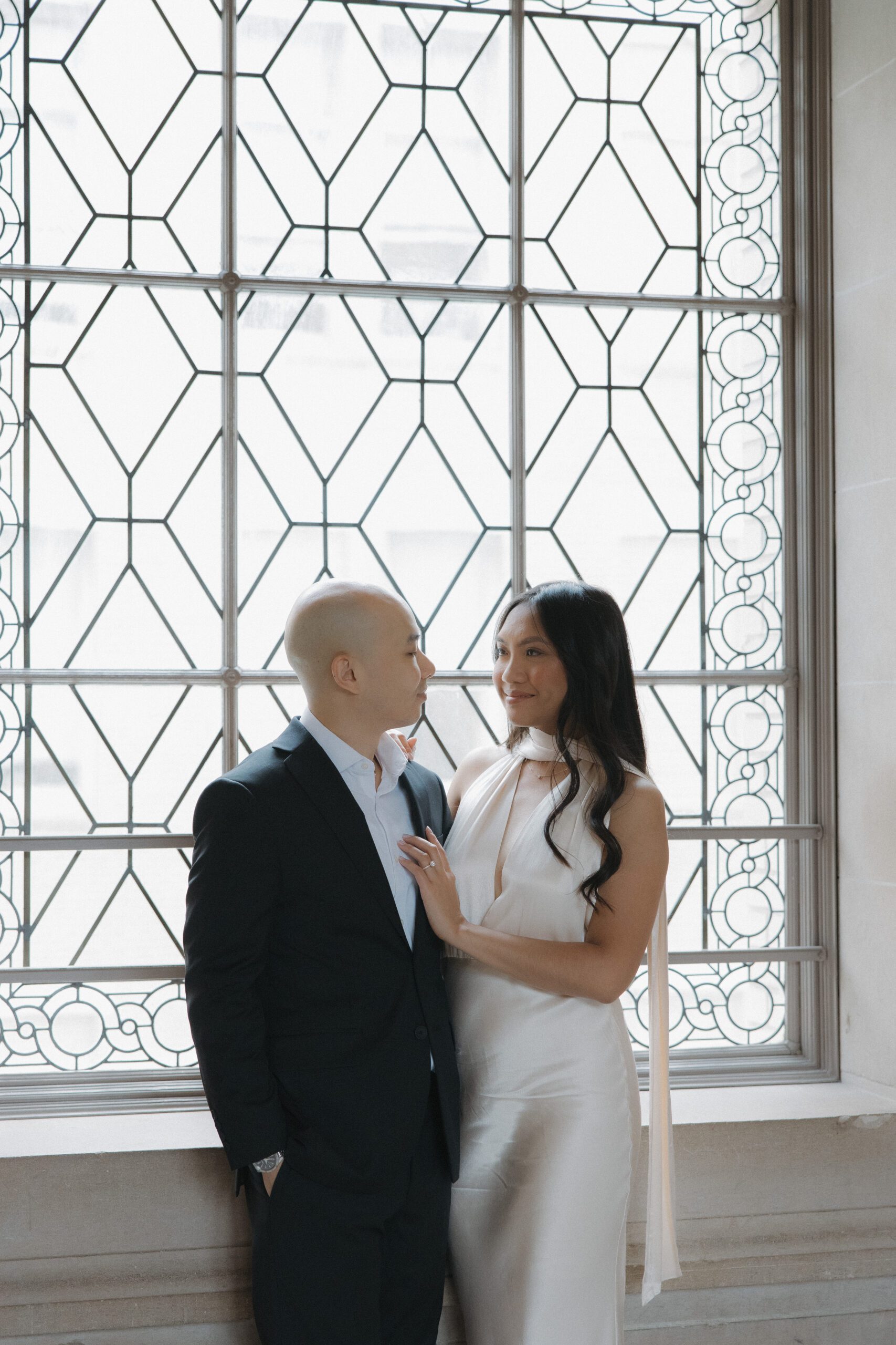 A couple posing in front of a window for their engagement photoshoot 