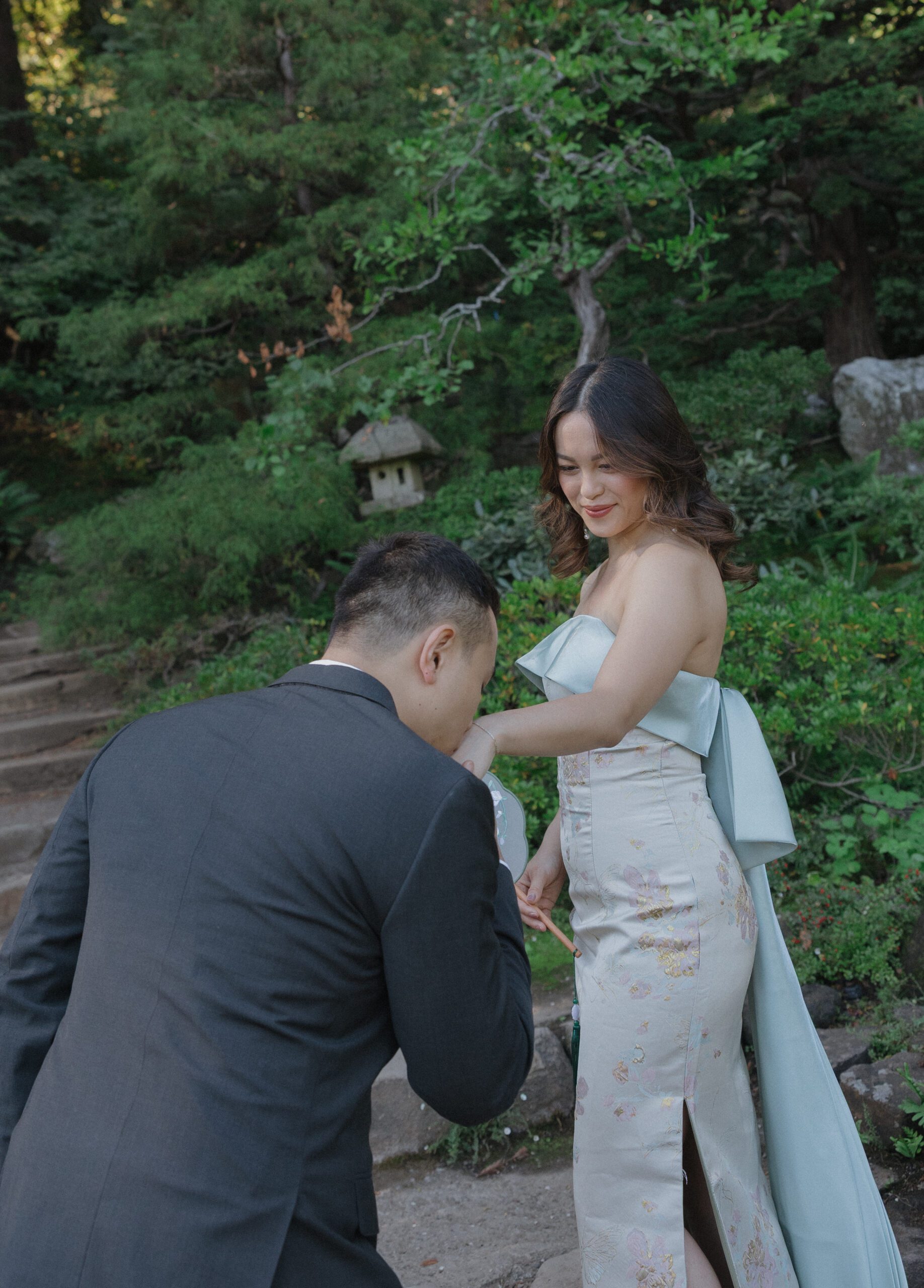 A man kissing his fiancees hand during engagement photos at Hakone Estate and Gardens