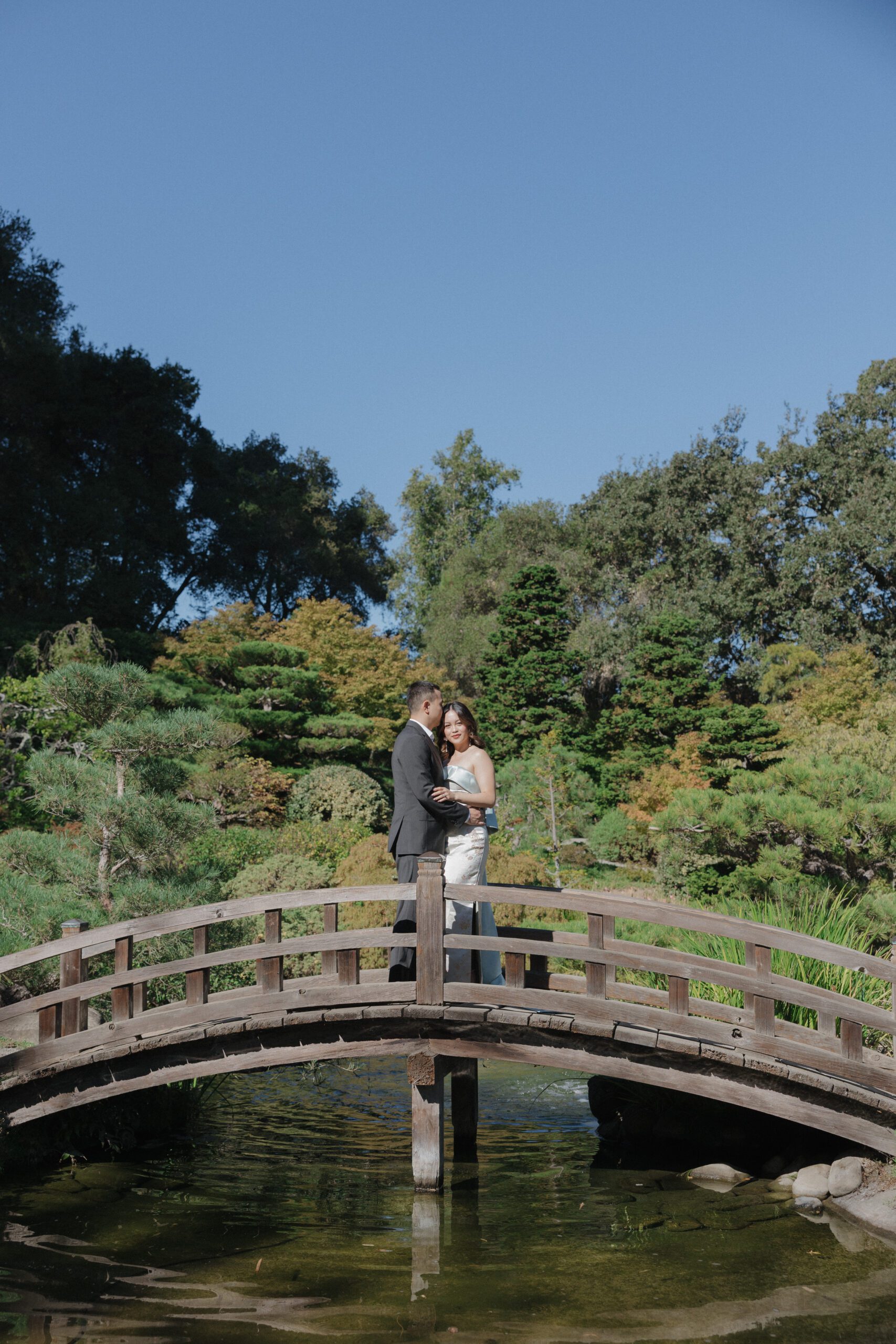 A couple posing for engagement photos on the Moon Bridge at Hakone Estate and Gardens