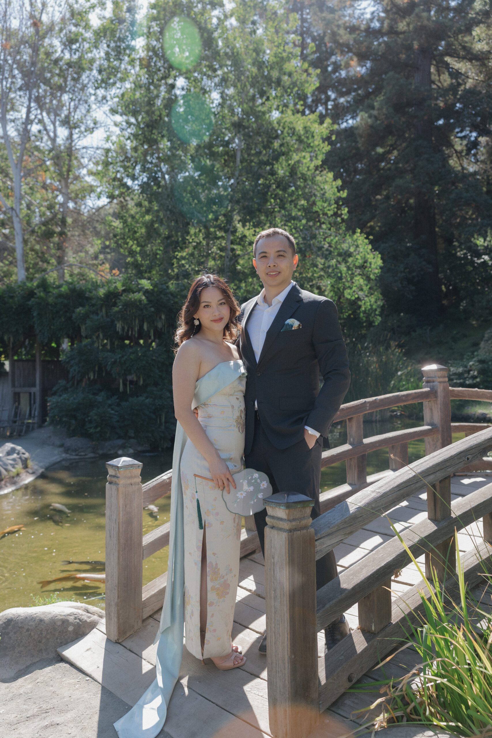 A couple posing for engagement photos next to a bridge