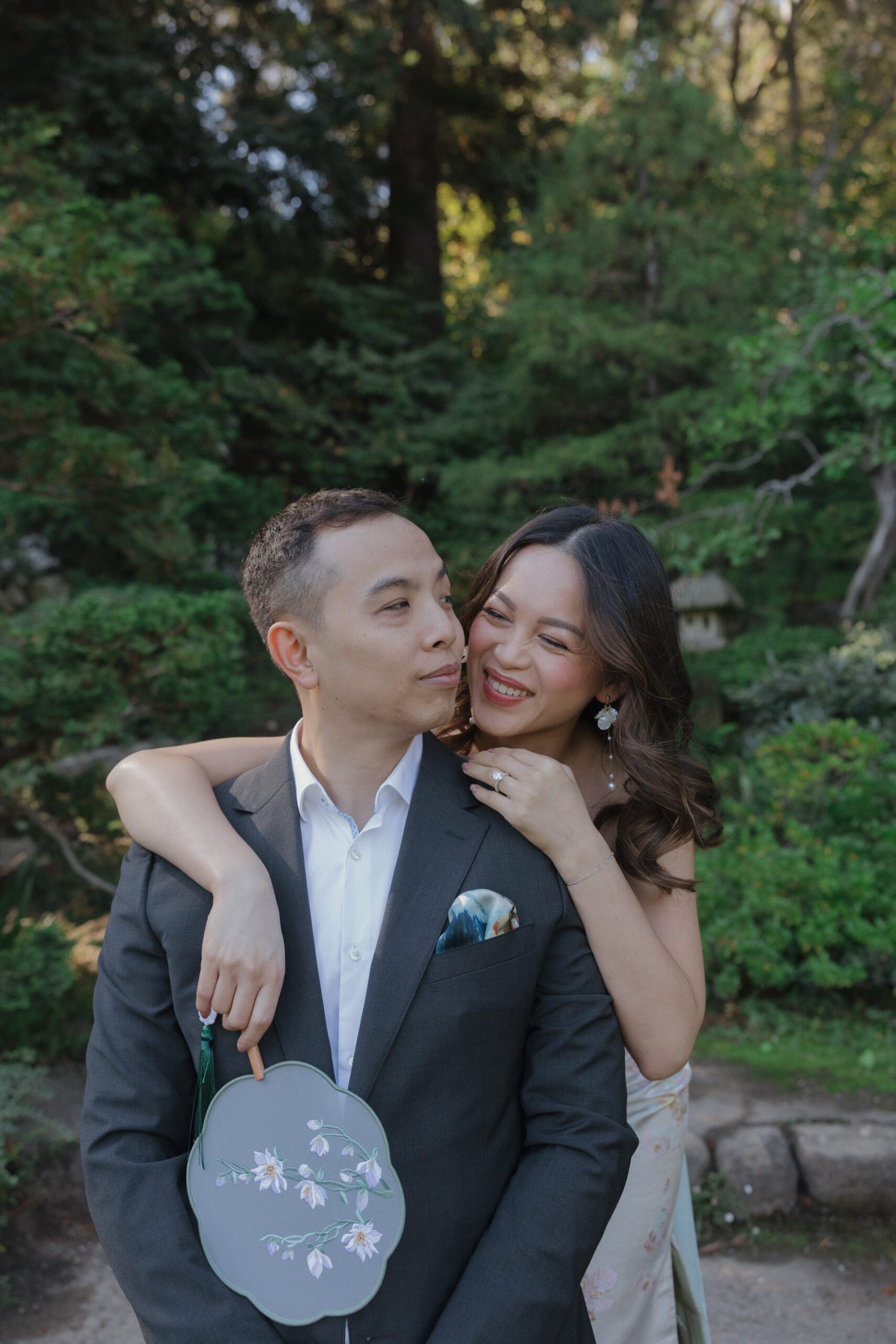 A girl laughing during engagement photos, leaning over her fiances shoulder