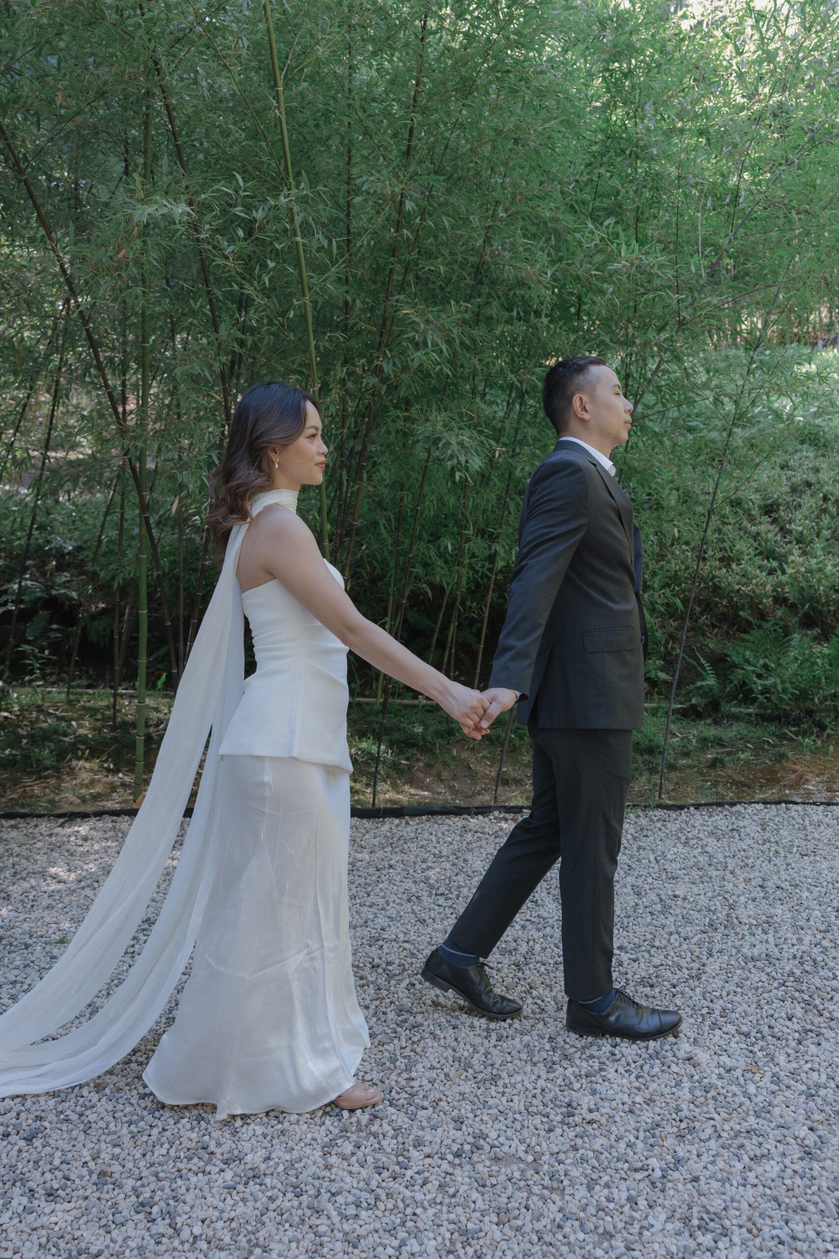 A couple holding hands walking in front of the bamboo forest at Hakone Estate and Gardens