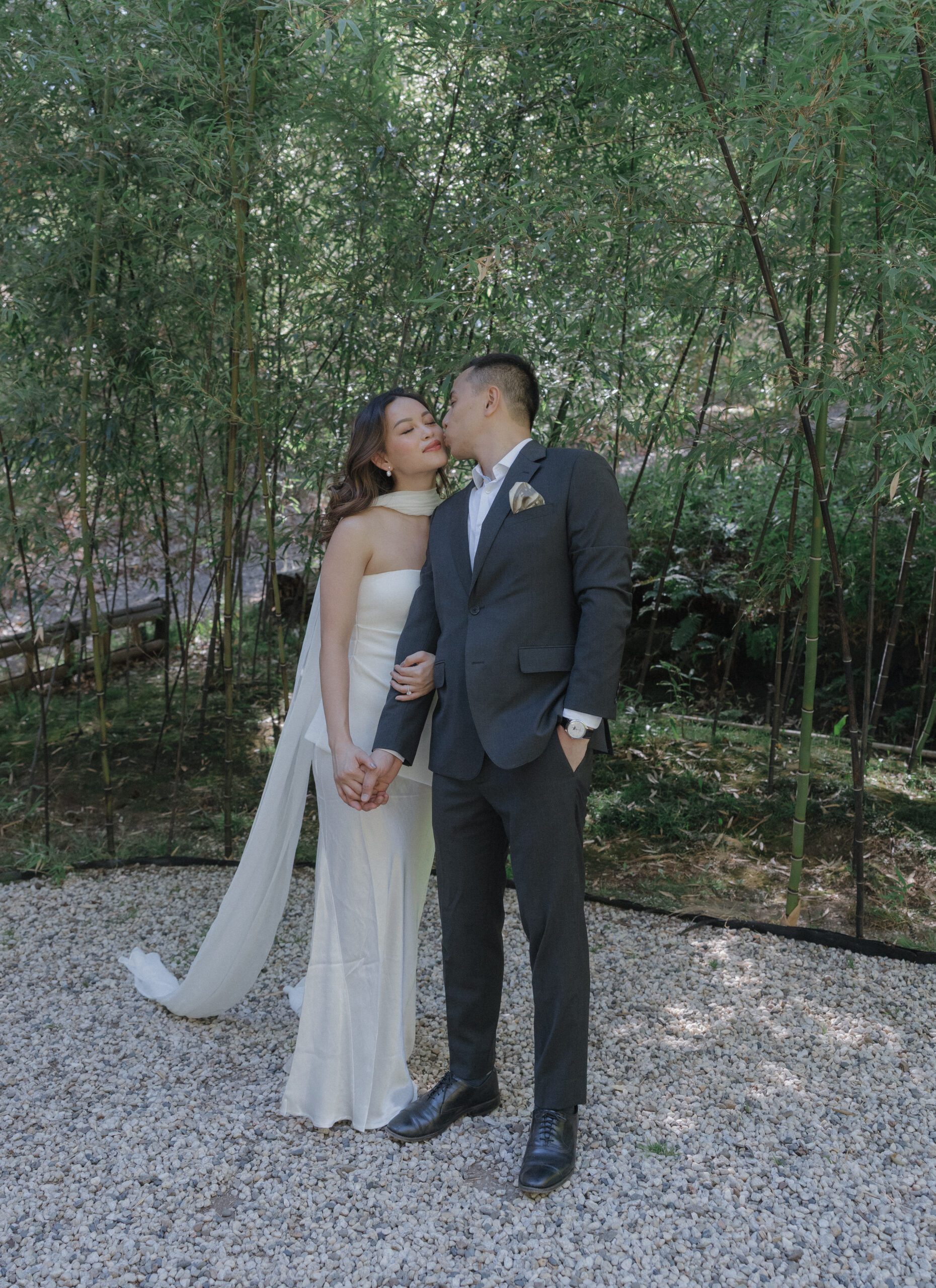 A man kissing a woman on the cheek during engagement photos in front of a bamboo garden