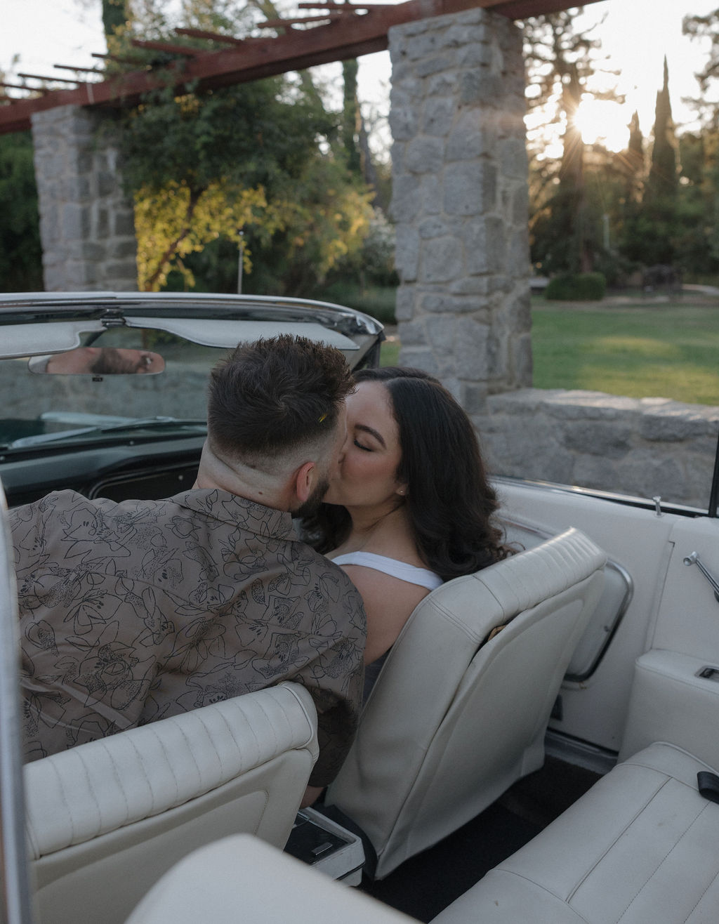 A couple kissing in a vintage car for their engagement photos