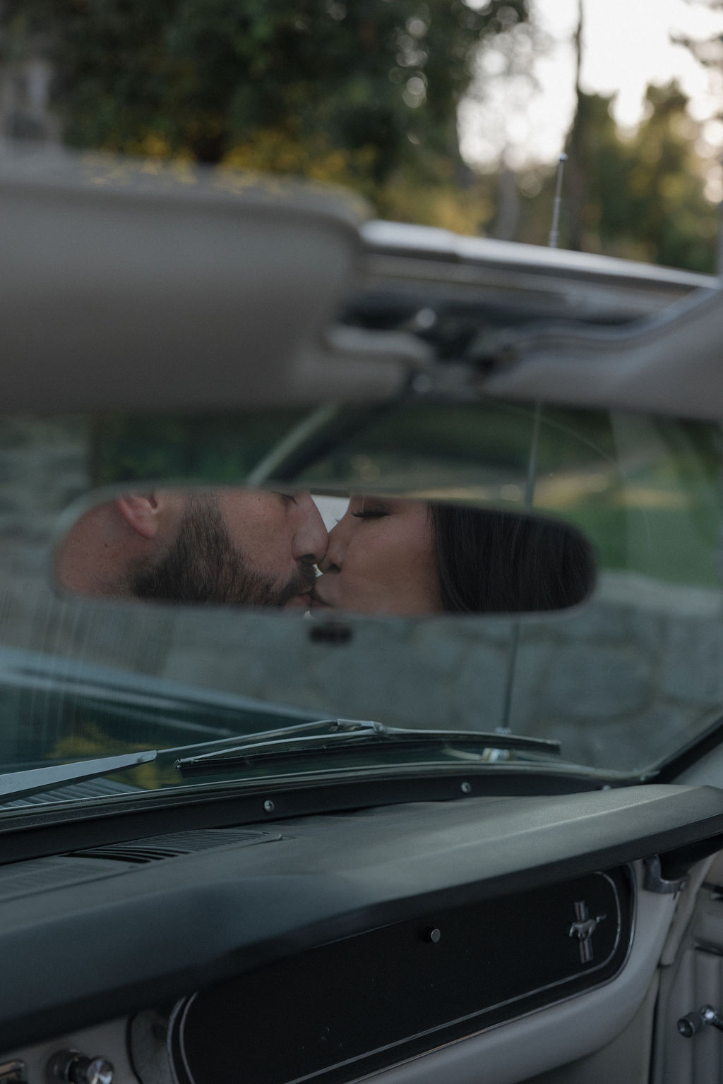 A couple kissing in a vintage car for their engagement photos