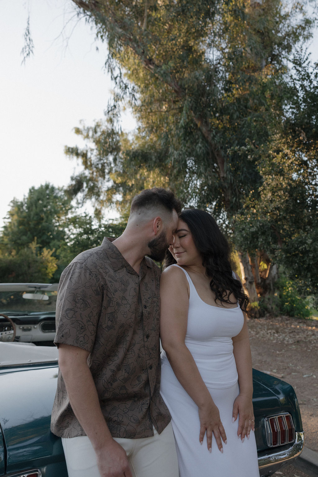 A couple posing with a classic car for engagement photos at William Land Park