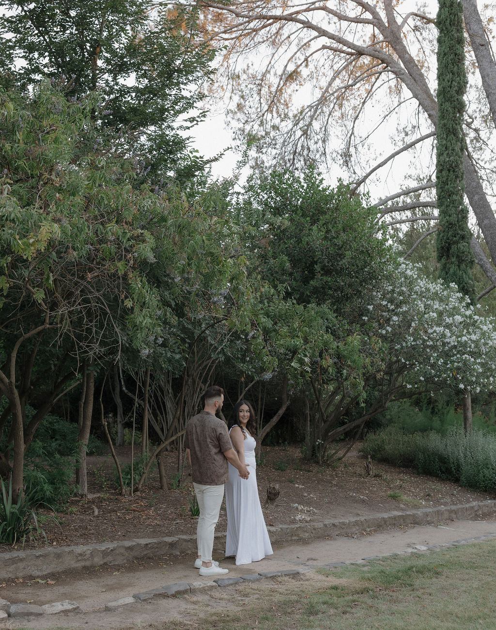 A couple walking through William Land Park in Sacramento for engagement photos