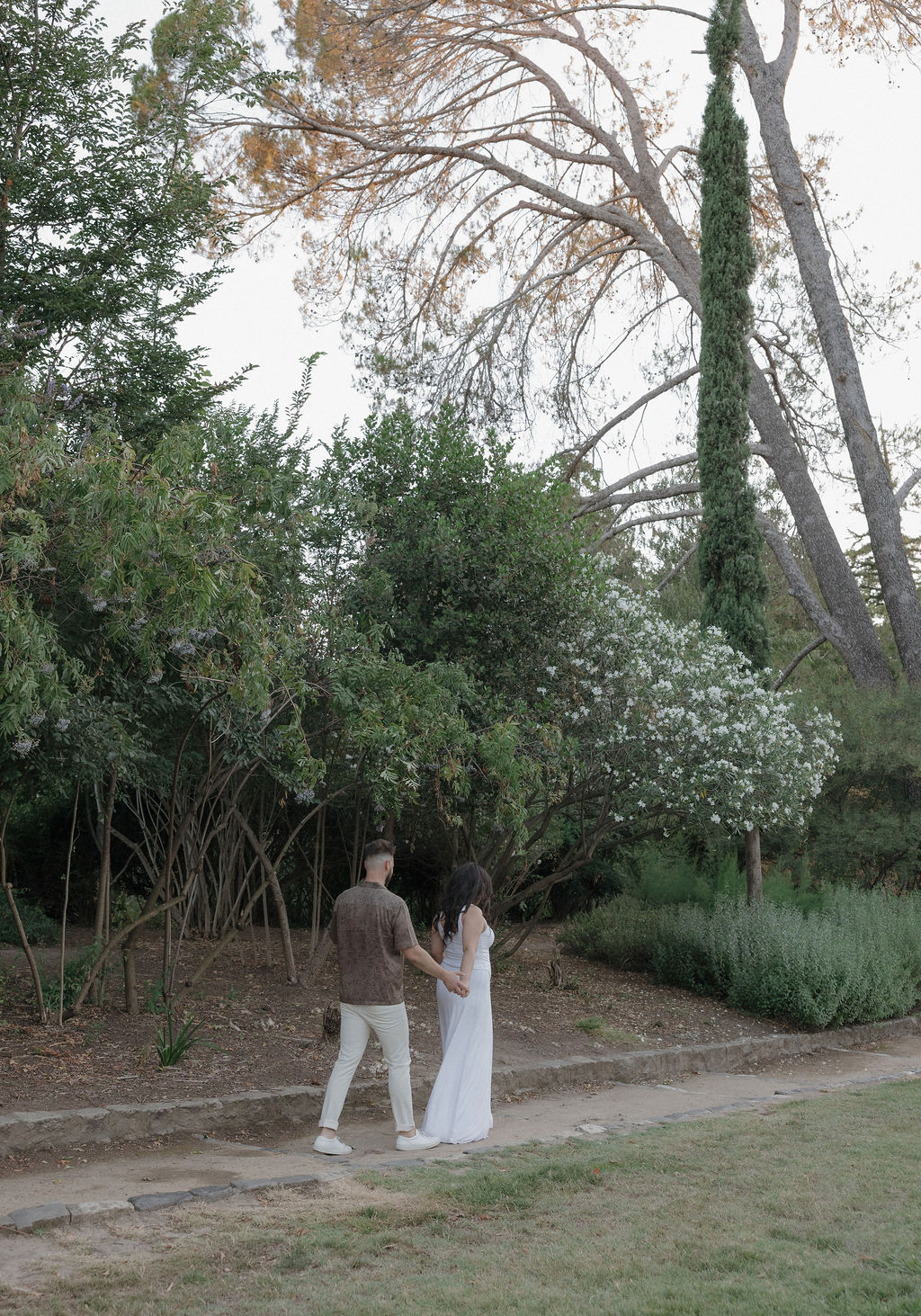 A couple walking through William Land Park in Sacramento for engagement photos