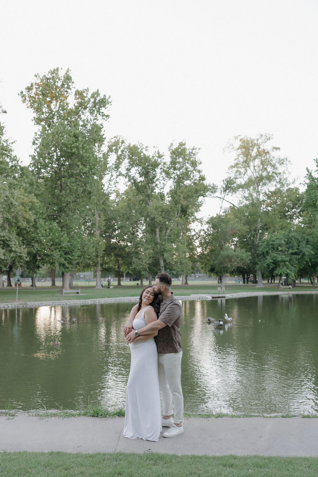 A couple posing In front of a pond for engagement photos