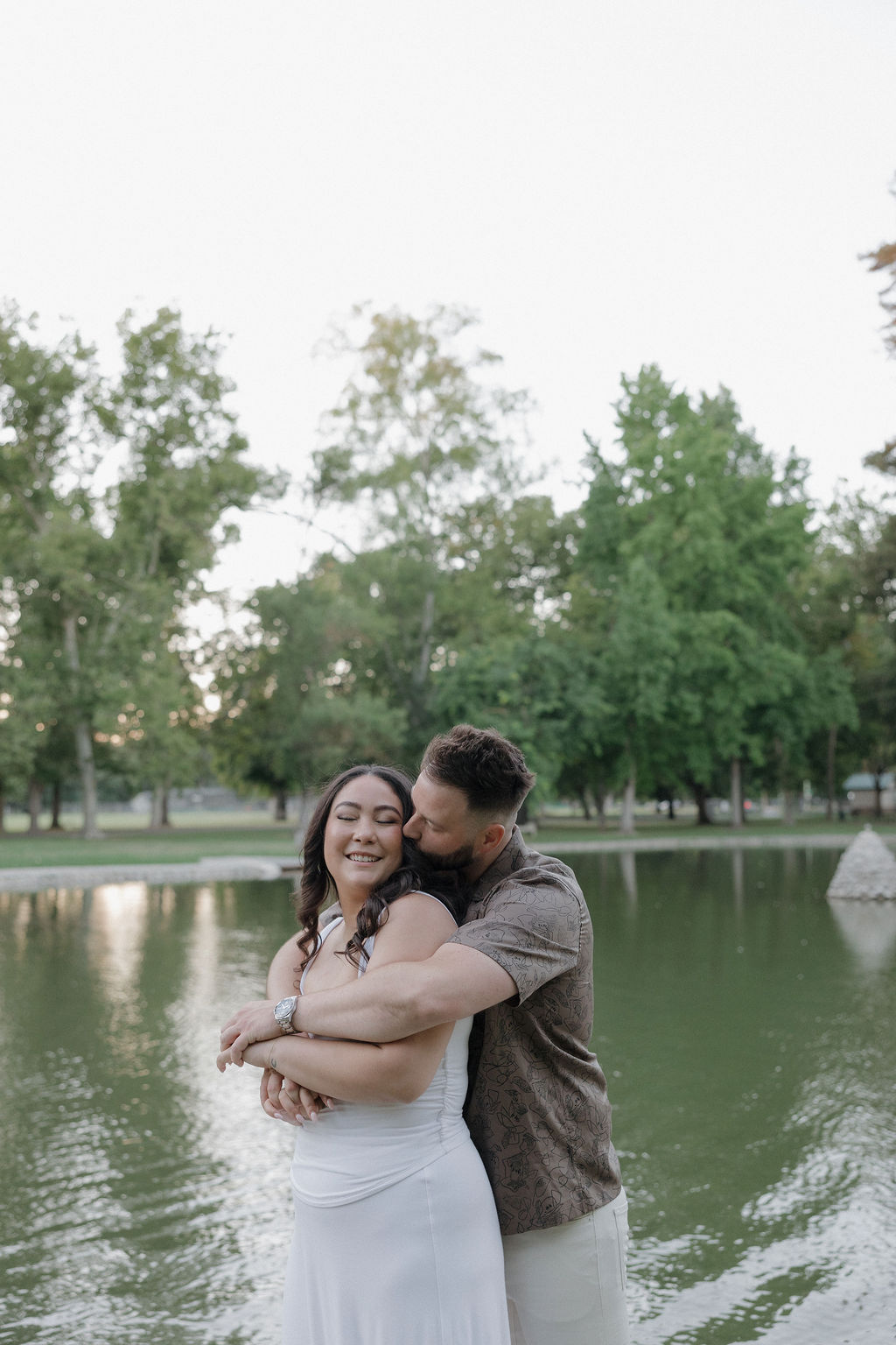 A couple posing In front of a pond for engagement photos