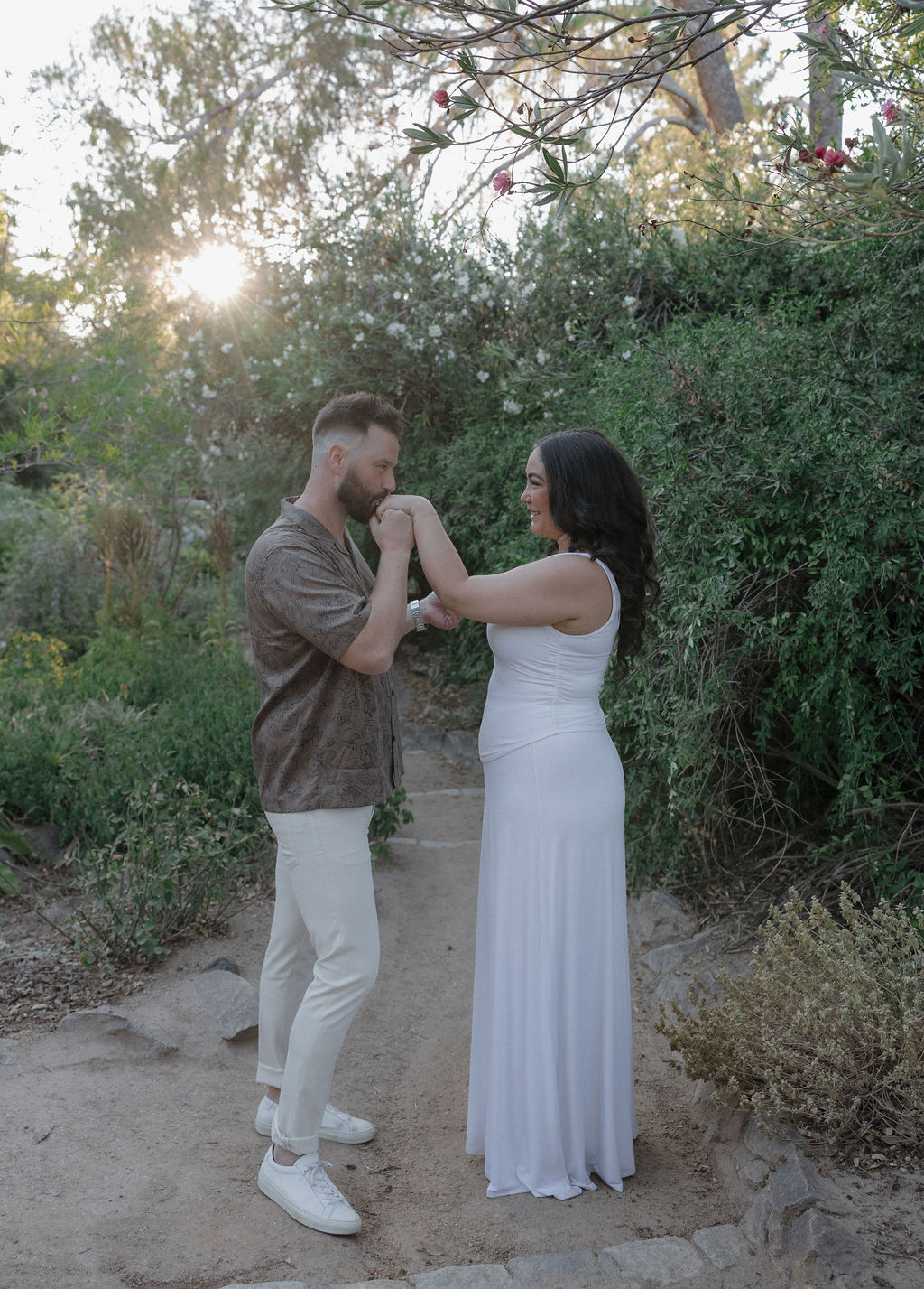 A man kissing his fiancees hand at their engagement photo location