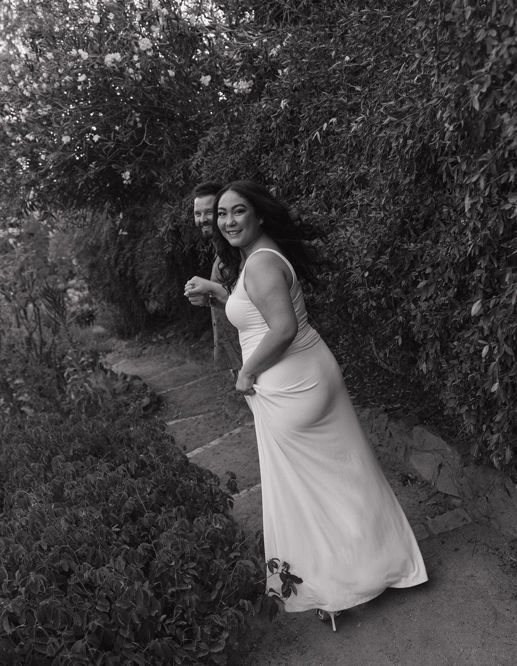 A couple walking through William Land Park in Sacramento holding hands for engagement photos