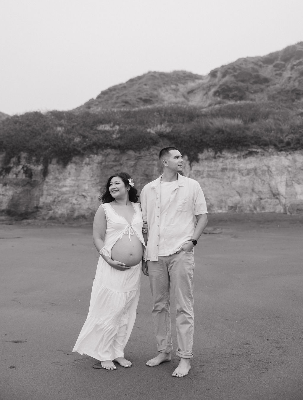 A couple posing on a beach for maternity photos