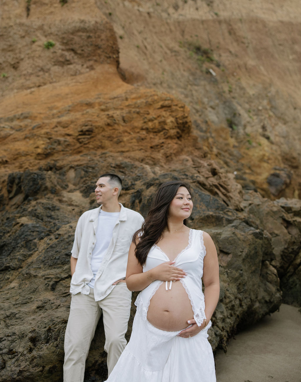 A couple looking in opposite directions during beach maternity photos
