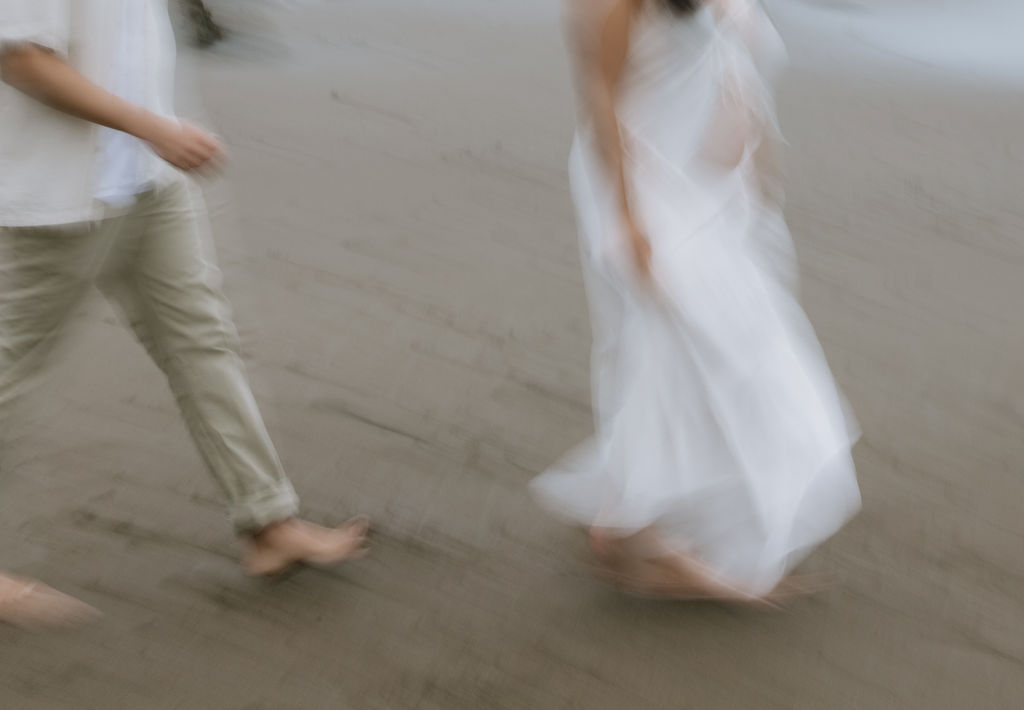 A blurry photo of a man and a woman walking on a beach during maternity photos