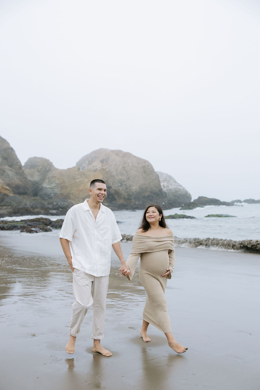 A couple walking on the beach for maternity photos