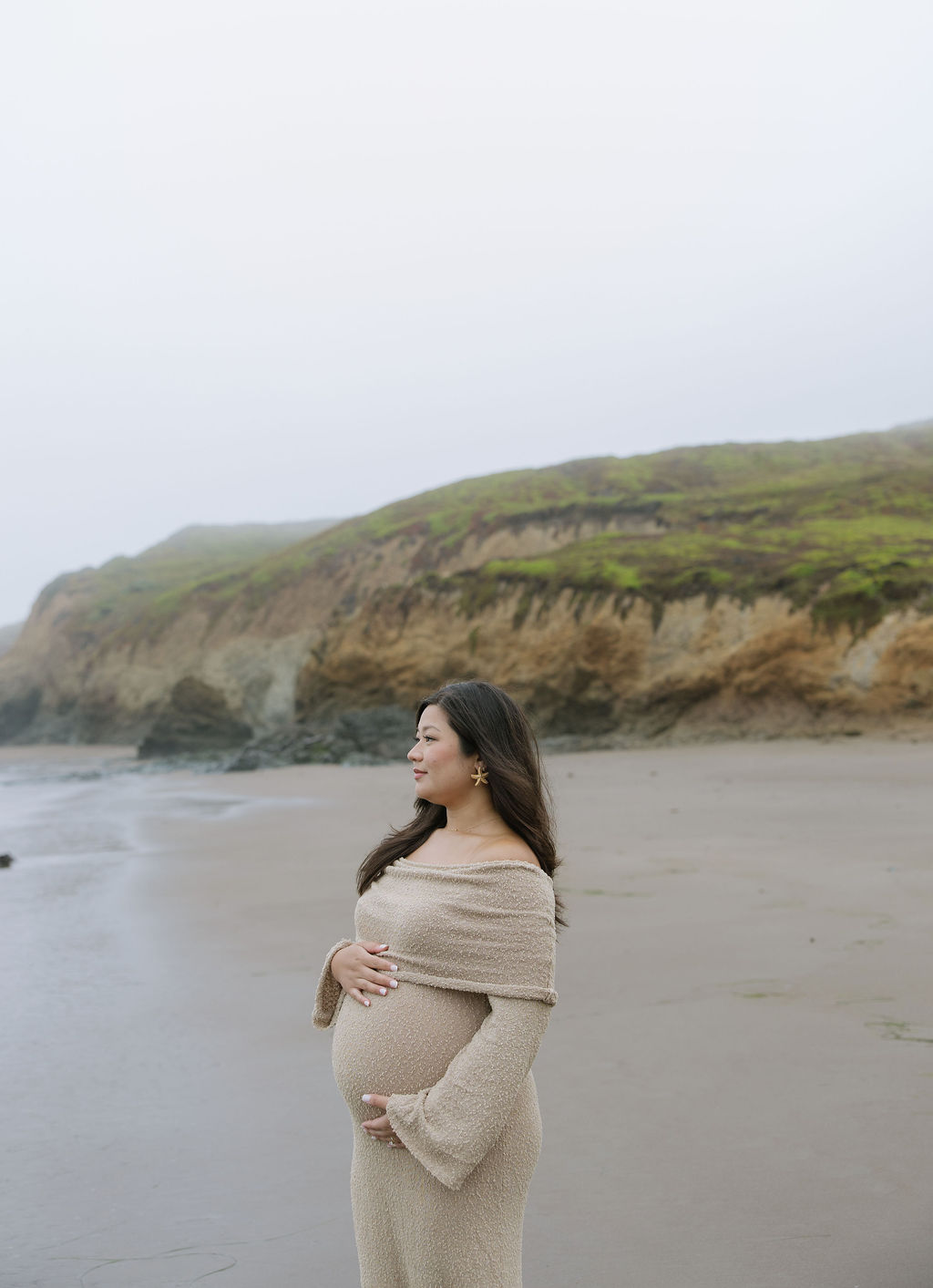 A woman posing for beach maternity photos