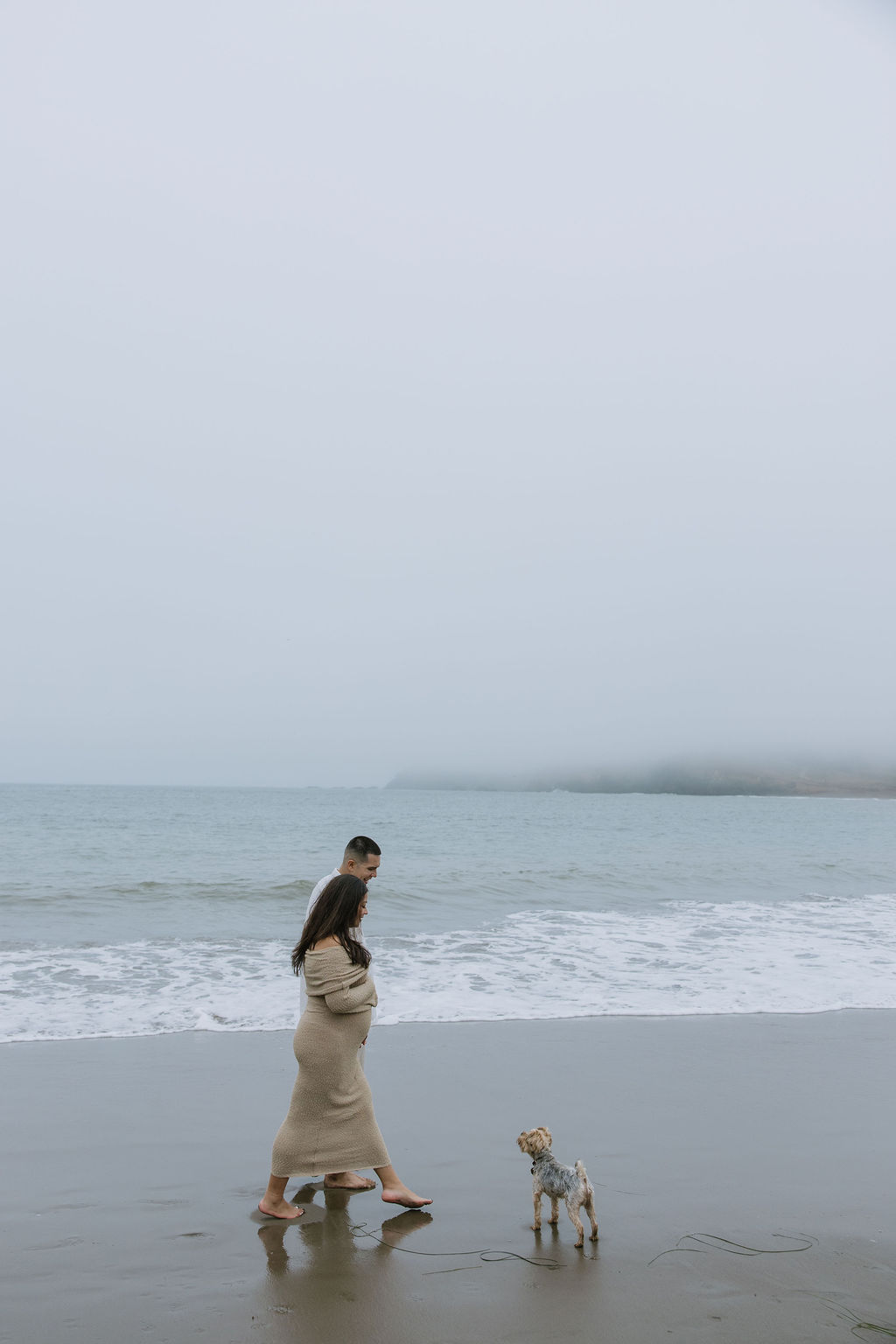 A couple walking on the beach for maternity photos