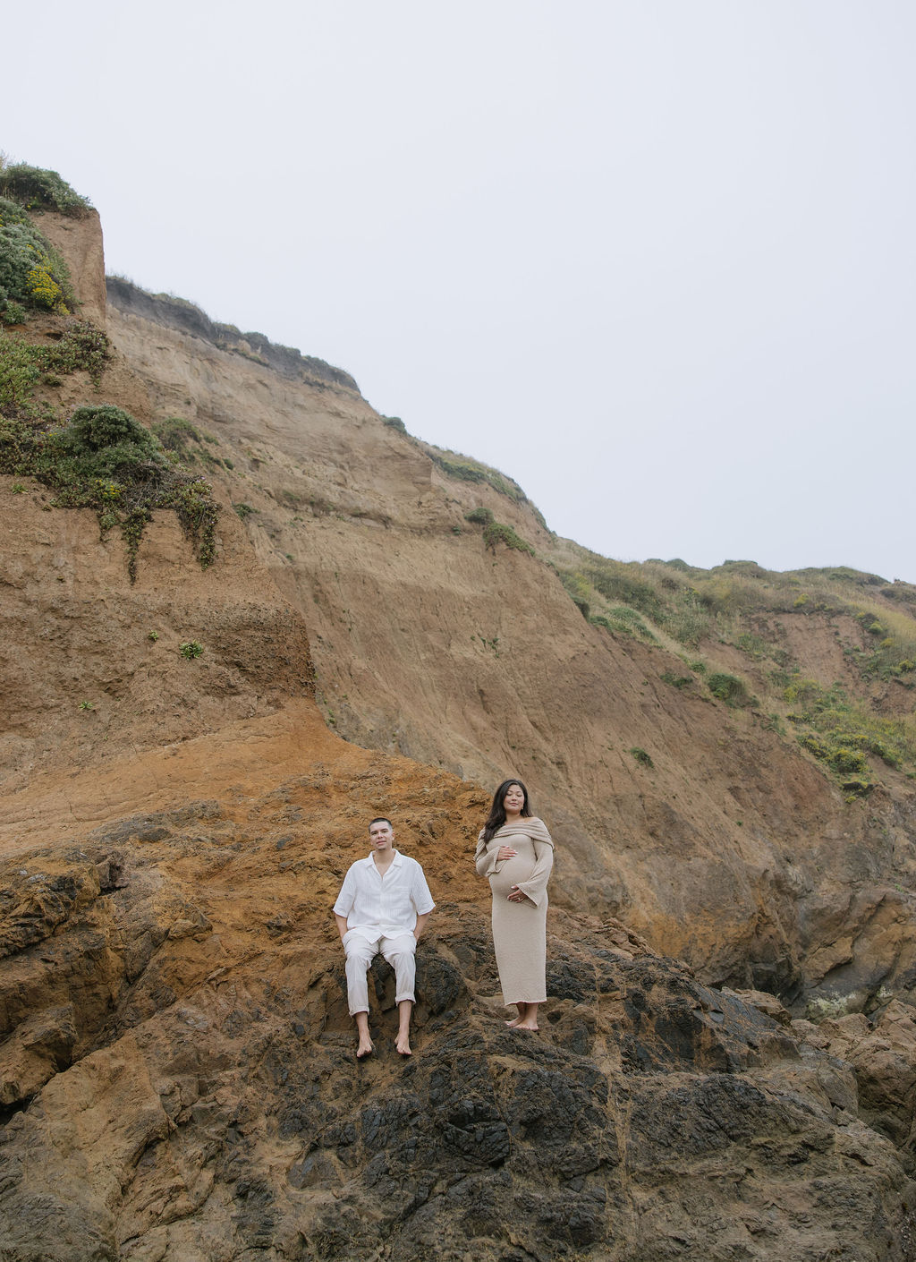 A couple posing on a rock for maternity photos