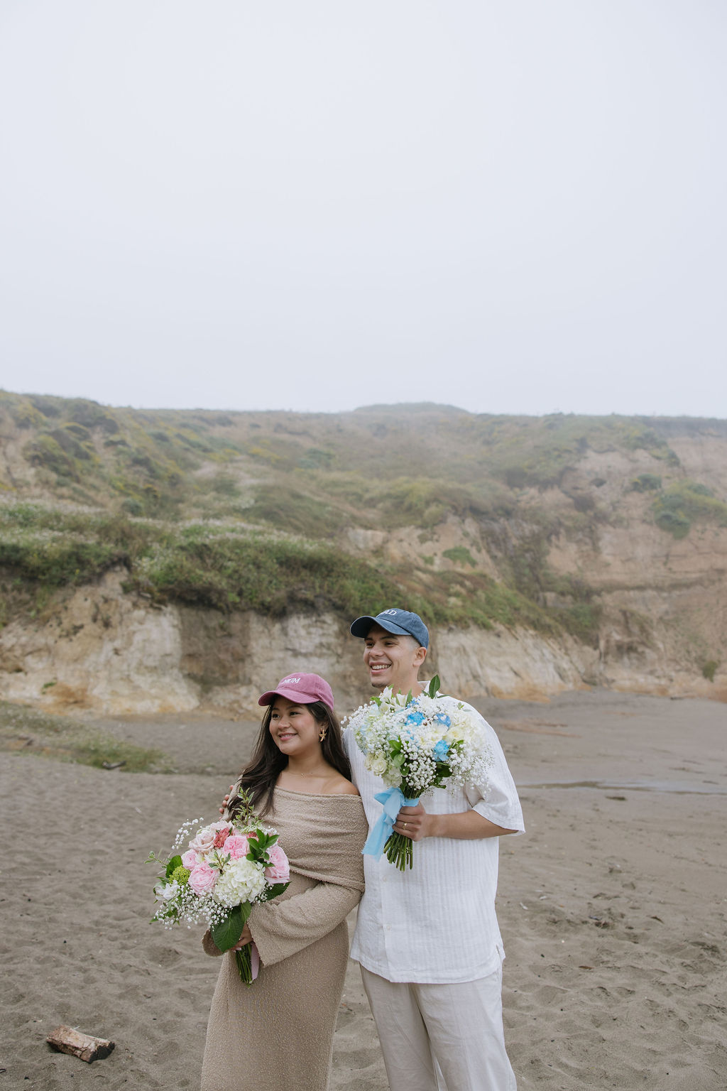 A couple wearing mom and dad hats for a beach maternity photoshoot