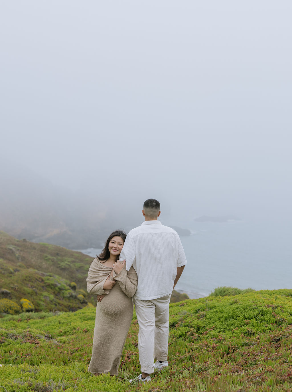 A woman holding her husband's arm during maternity photos