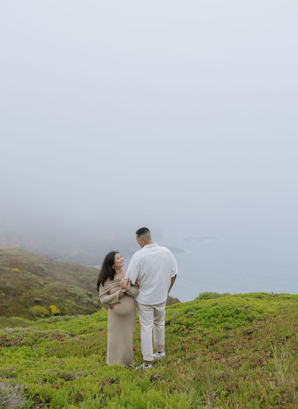 A woman holding her husband's arm during maternity photos