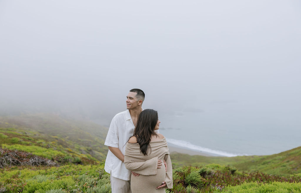 A couple posing overlooking a beach during a maternity session