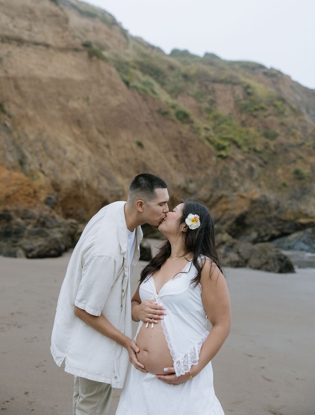 A couple kissing during beach maternity photos